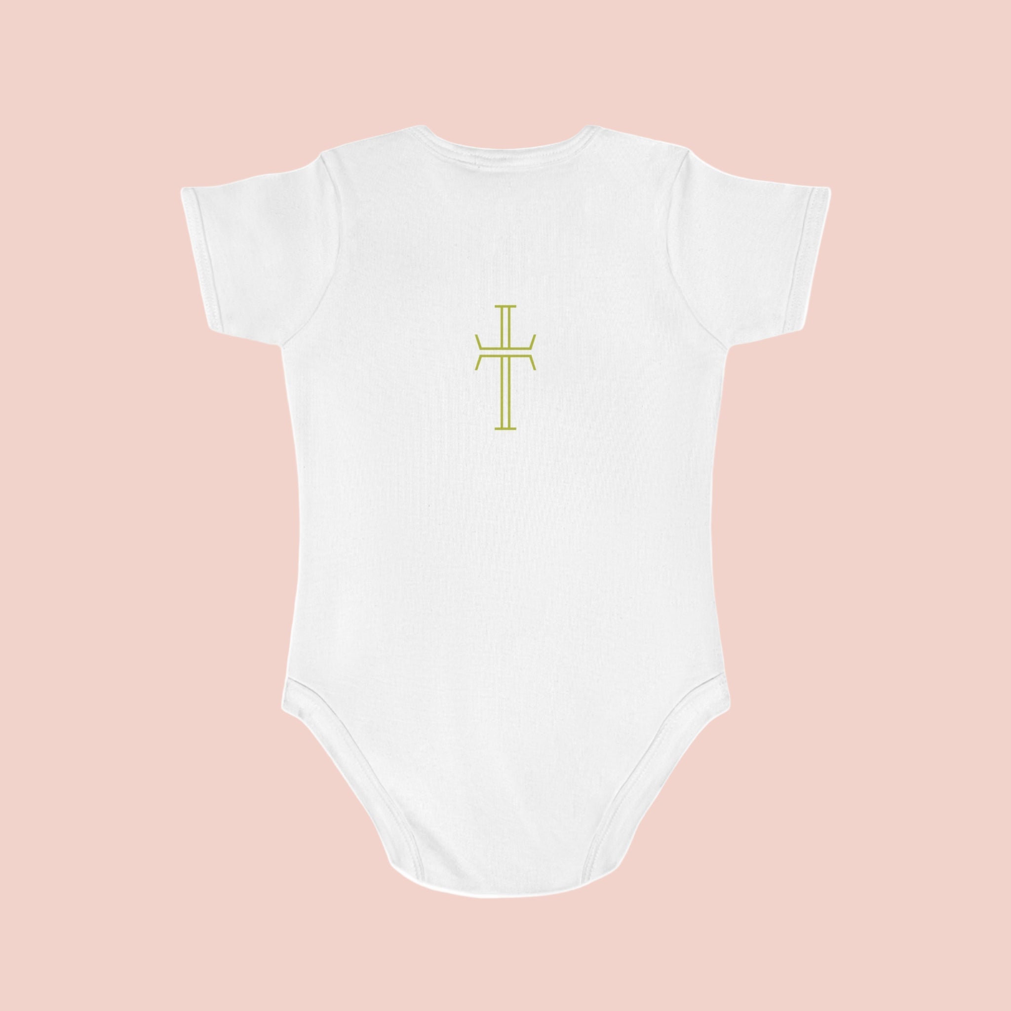 White baby onesie with a yellow cross design on a pale pink background