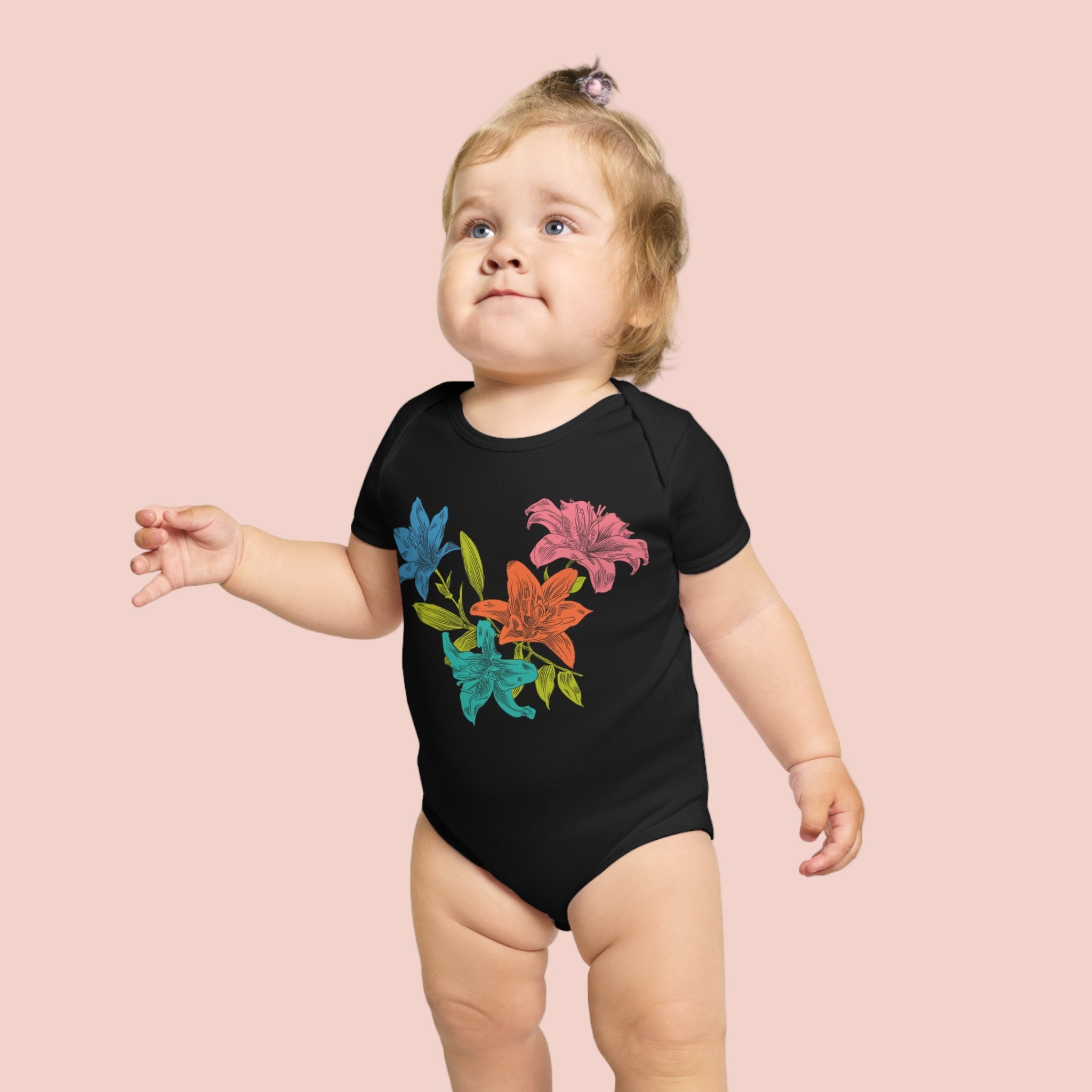 Child wearing a black onesie with colorful floral designs on a white background