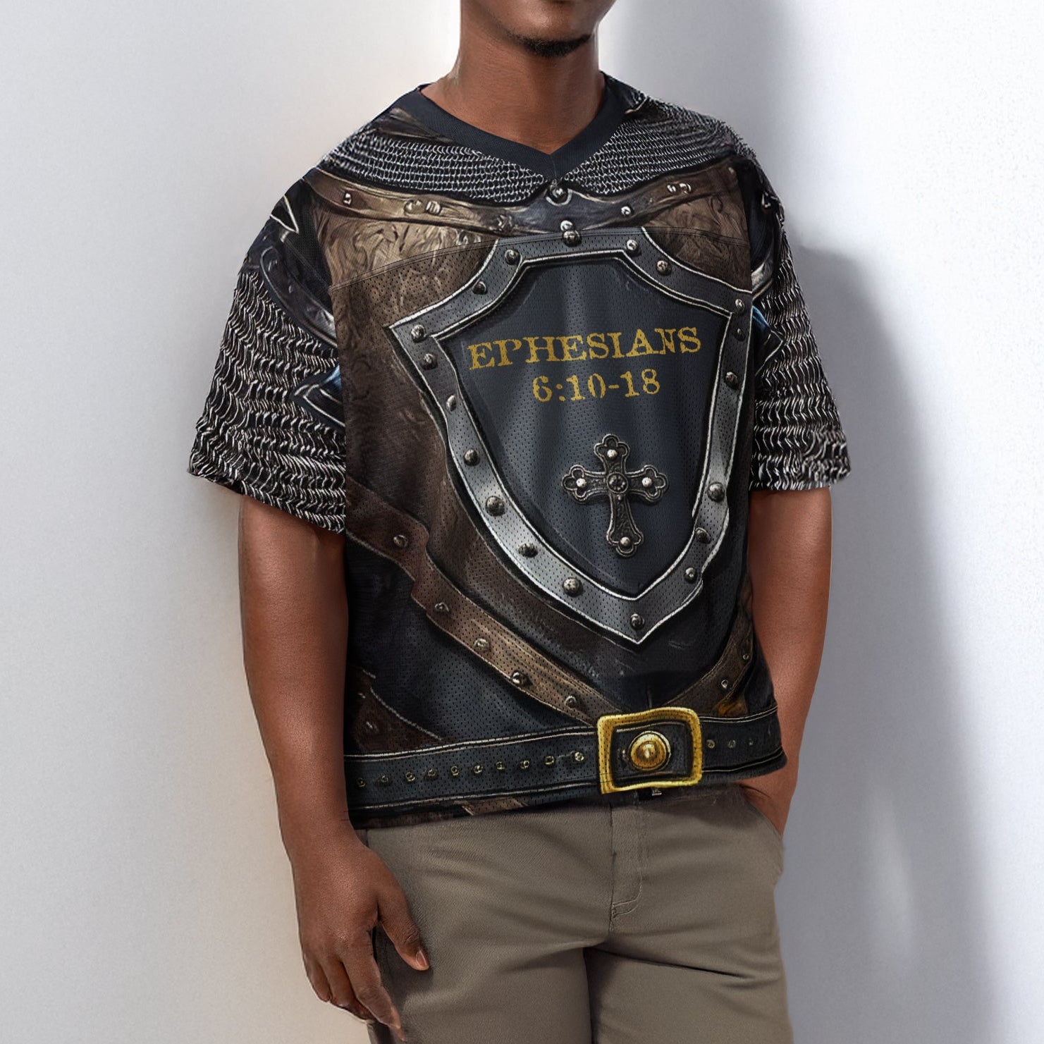Man wearing a shirt decorated with armor-like design and Biblical text on a plain background