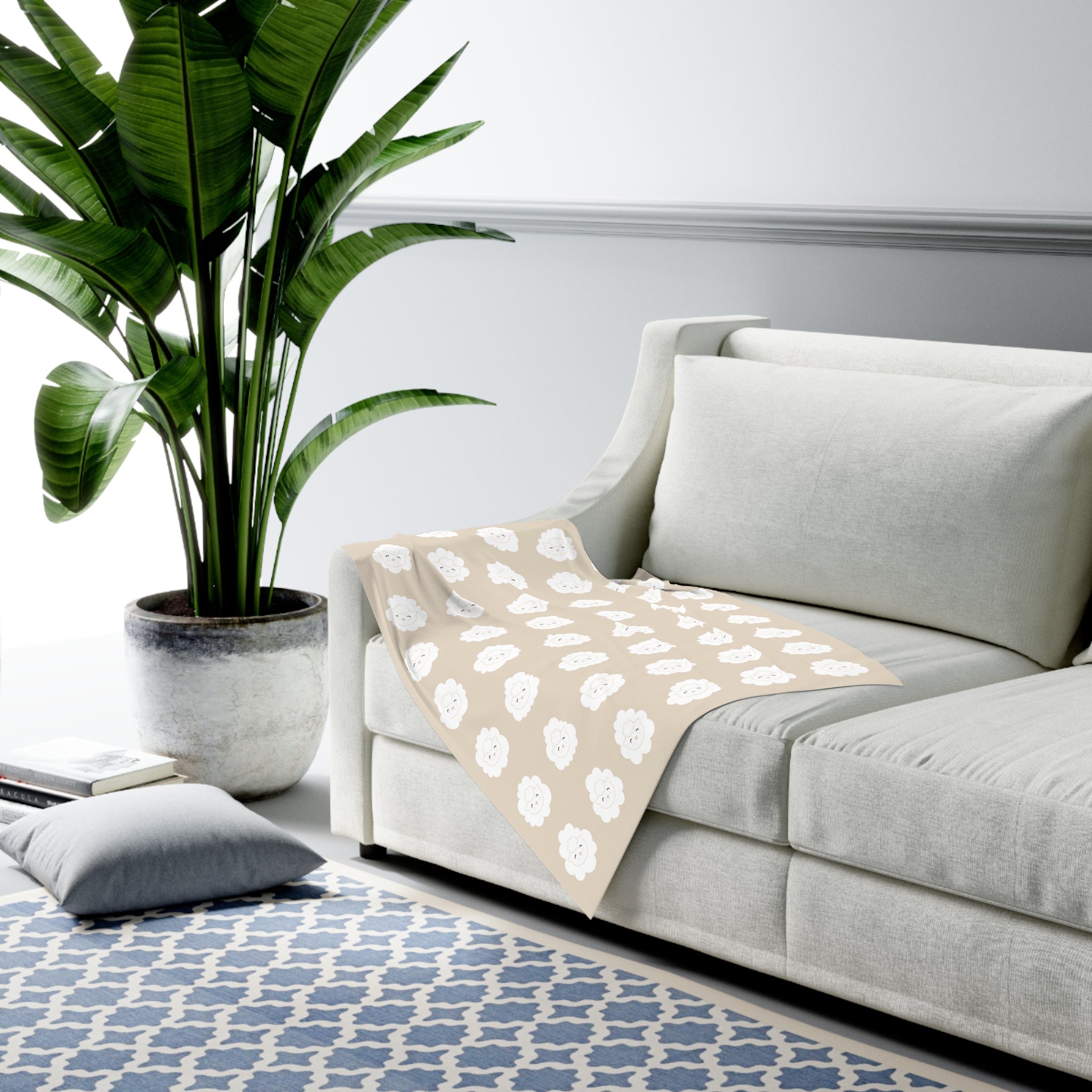 Gray sofa with a lamb patterned blanket, with plant and rug in a living room setting.