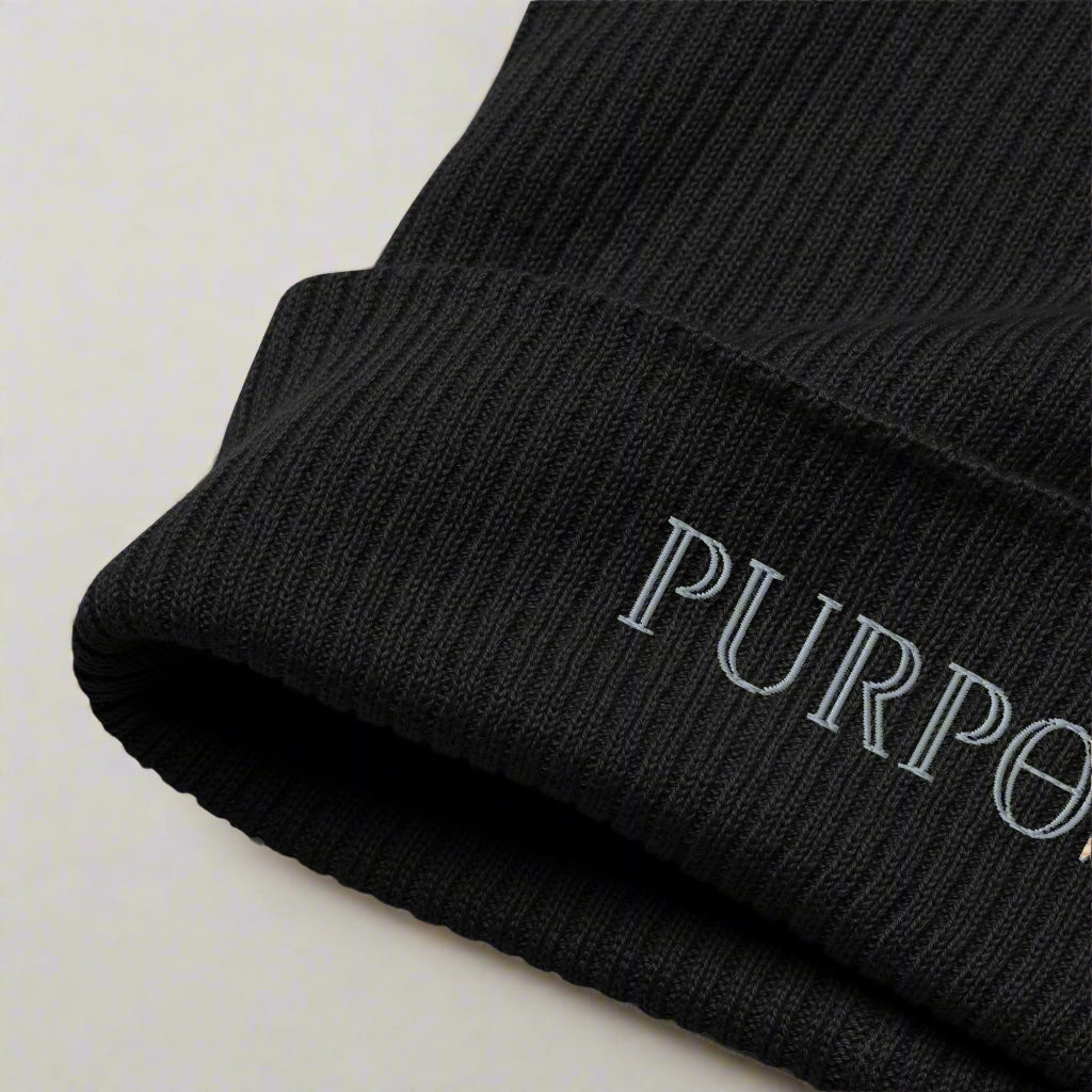 Black beanie with 'PURPOSE' embroidered on a light background