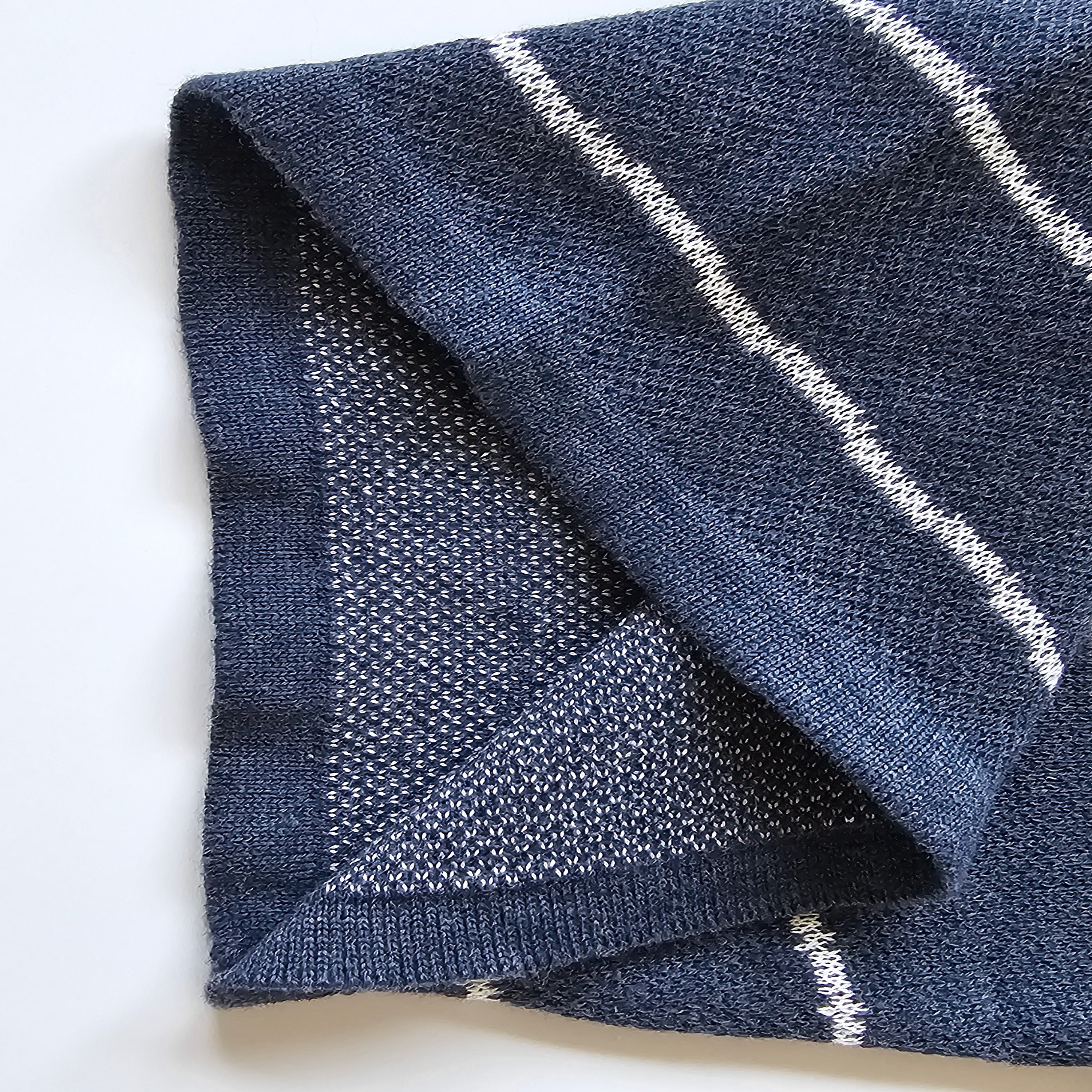Folded blue knitted fabric with white lines on a white background