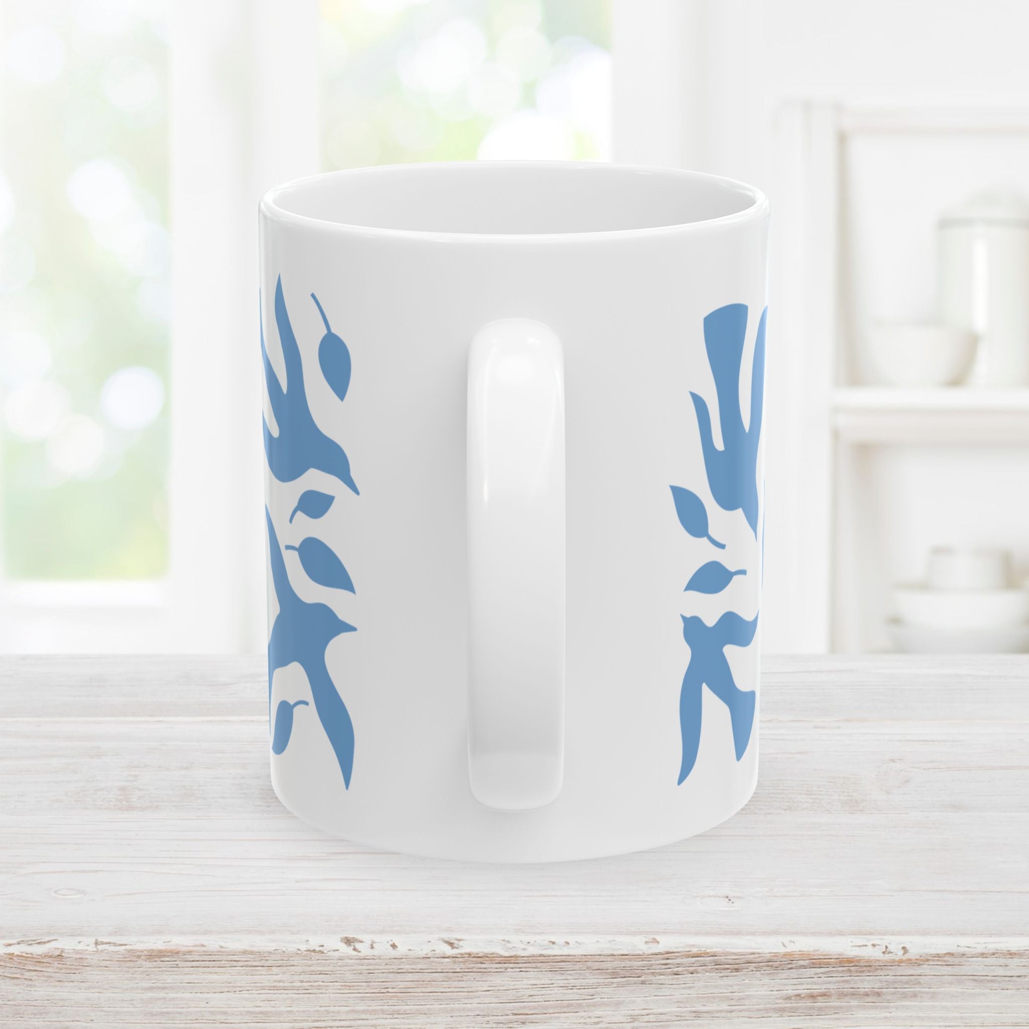 11oz white mug with blue dove and leaf pattern on a light wooden surface