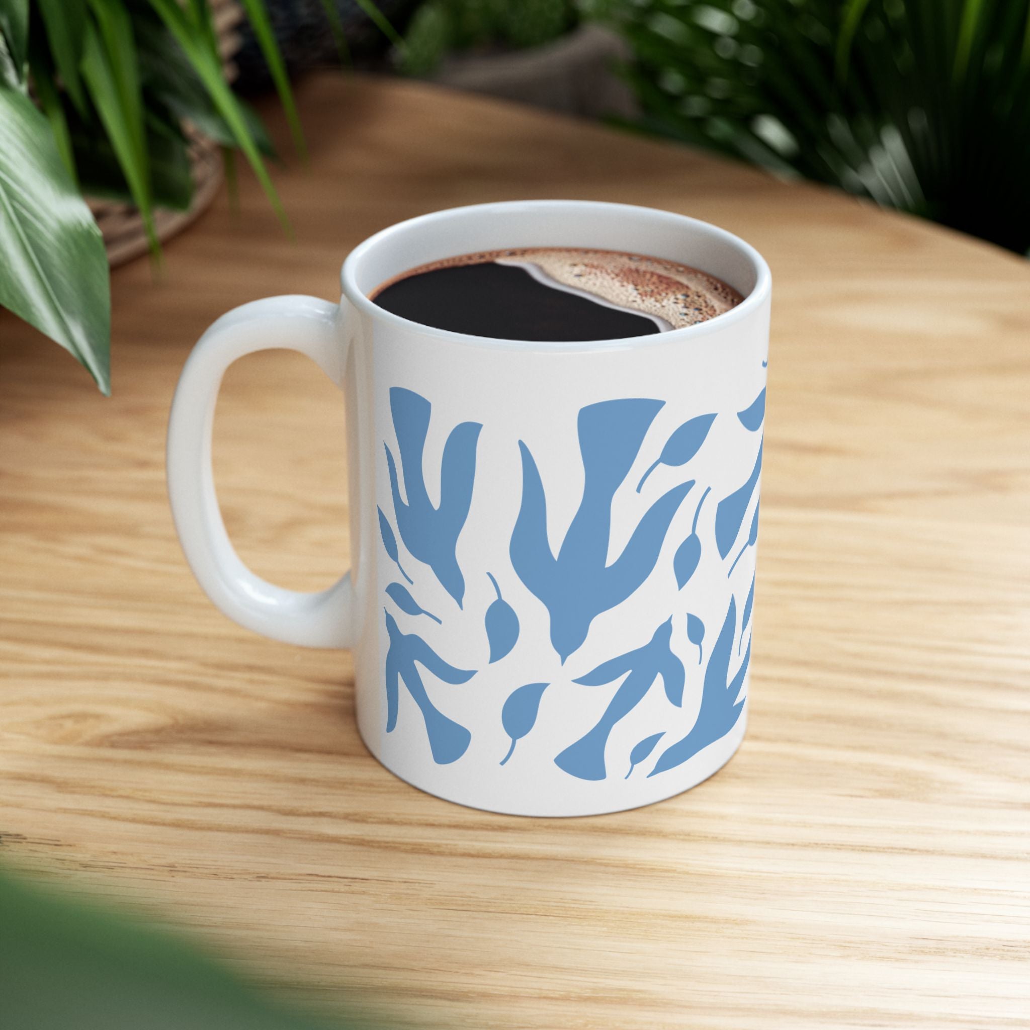 11 oz white mug with blue dove and leaf pattern on a wooden table with coffee.