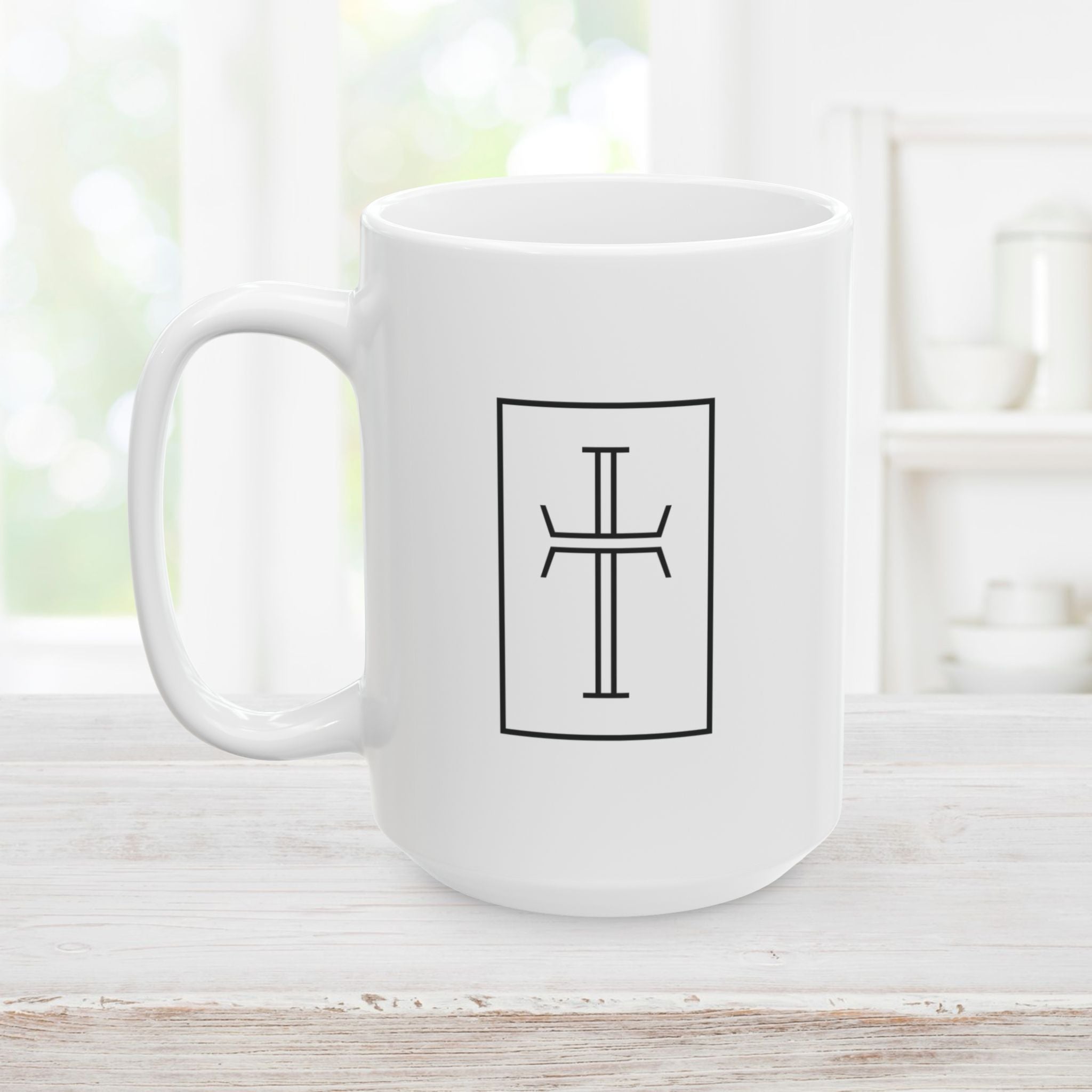 Right side of 15 oz white mug with a black cross on a light wooden surface.