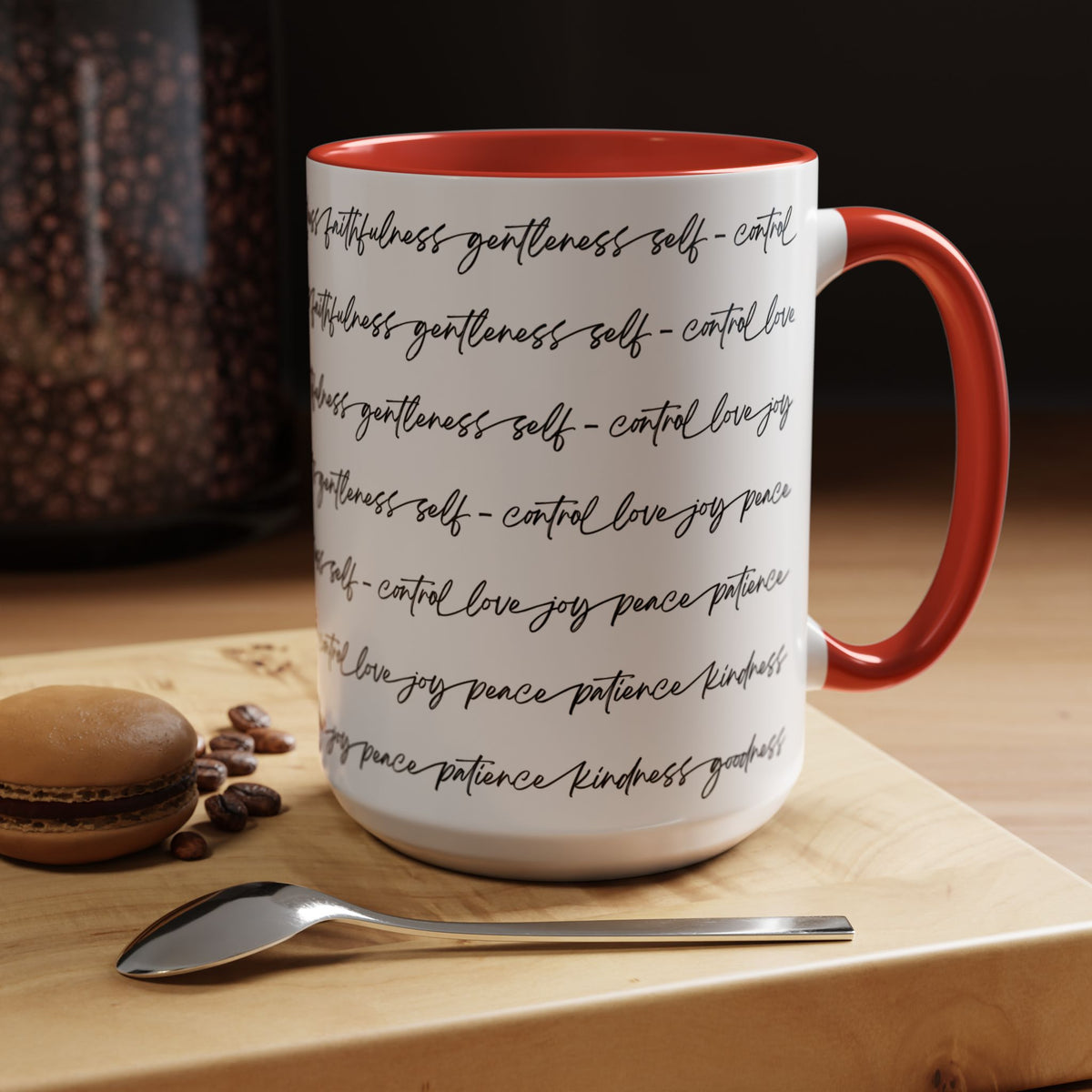 Right side of 15oz mug with red interior and handle with black scripted text written on a white background sitting on a wooden surface with coffee beans and a spoon.