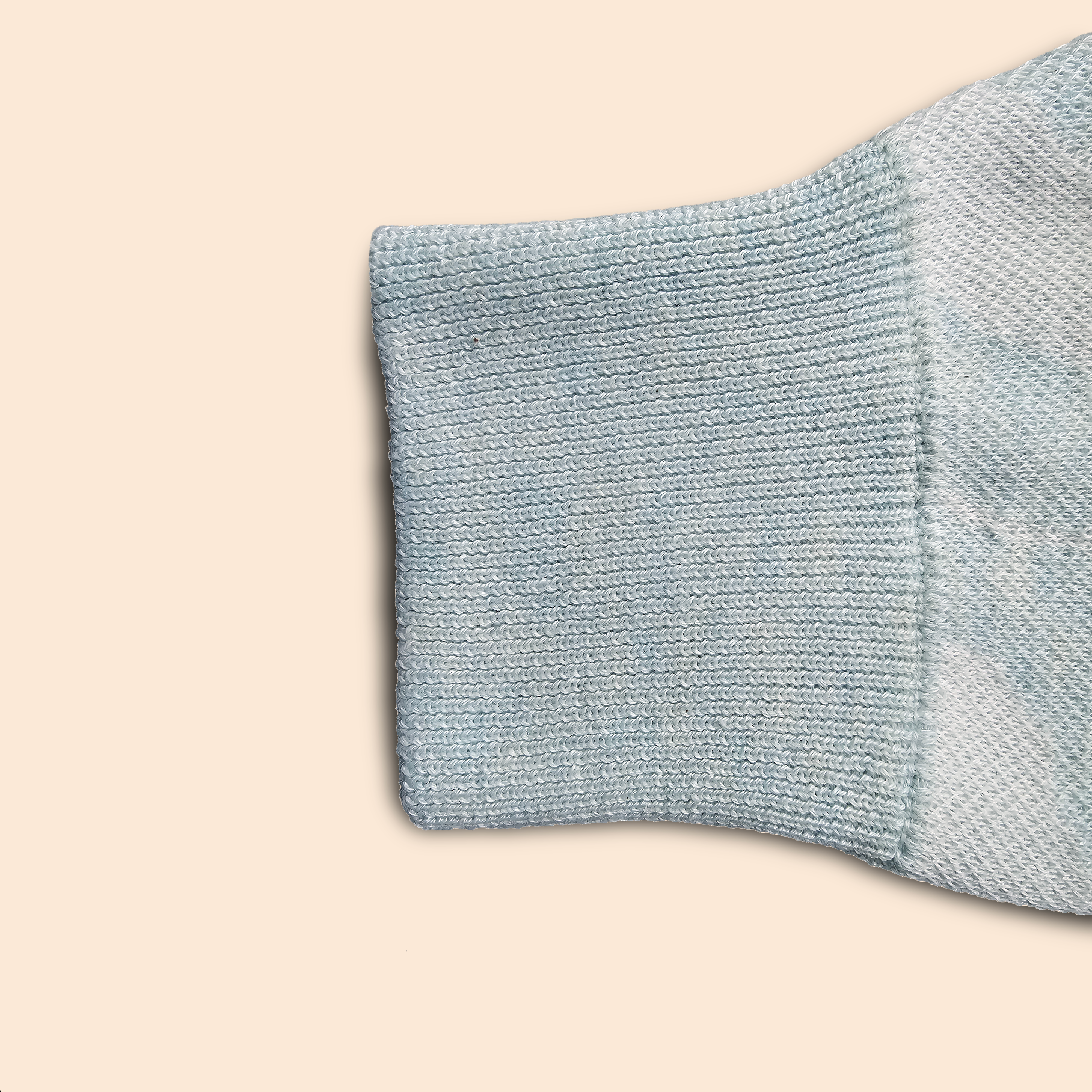 Close-up of the knittedcuff of a light blue sweater on a beige background