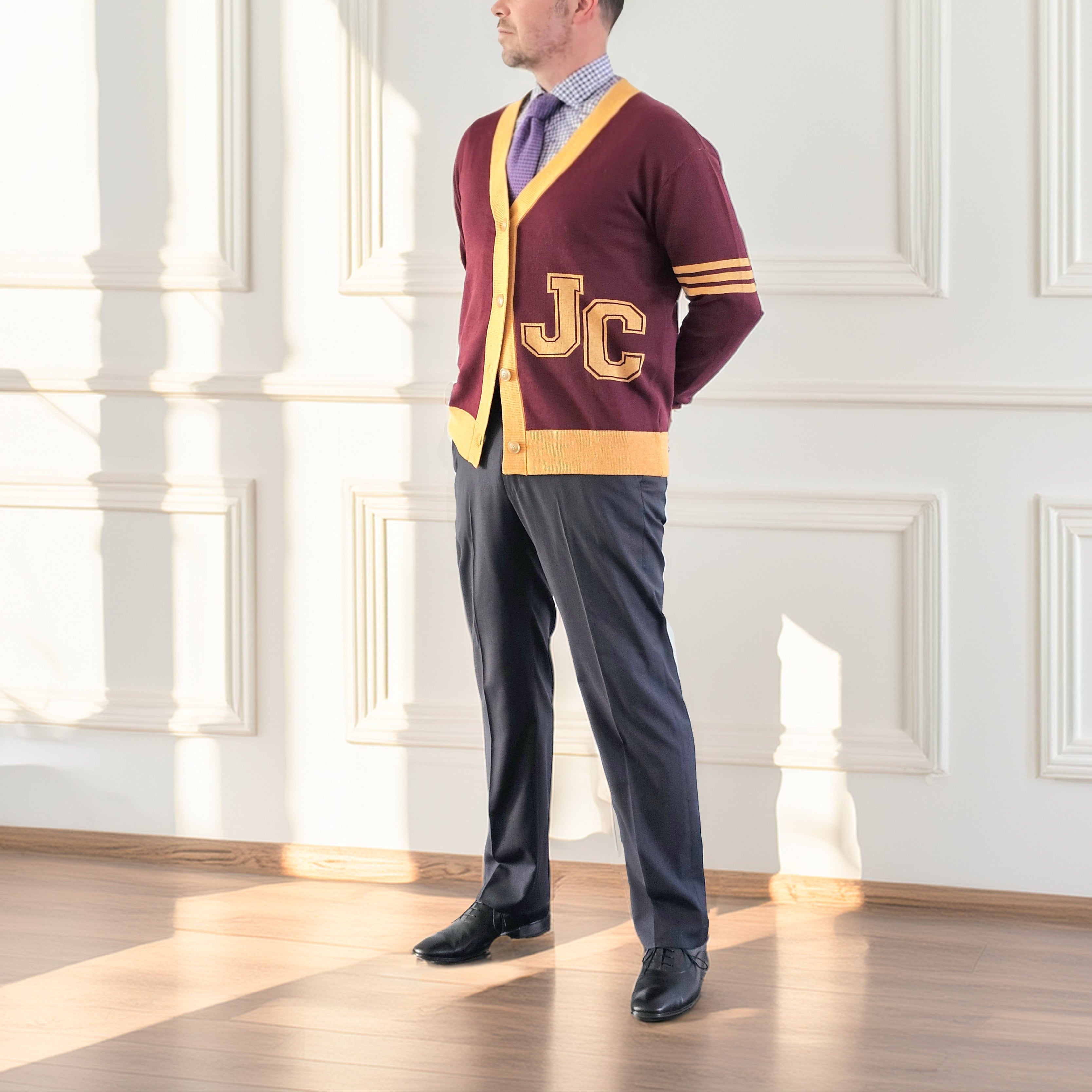 Man wearing a maroon sweater with 'JC' letters in a bright room
