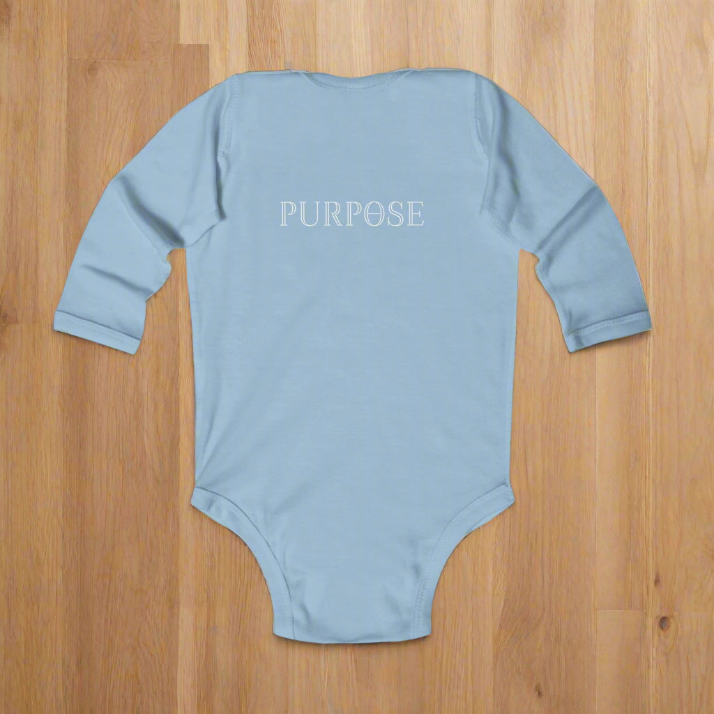Light blue baby onesie with 'PURPOSE' text on a wood floor background