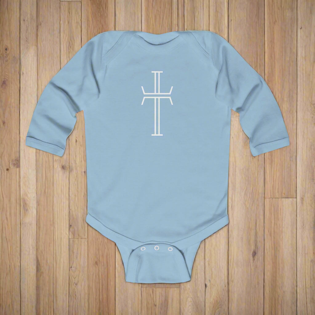 Light blue baby onesie with a white cross design on a wood floor background