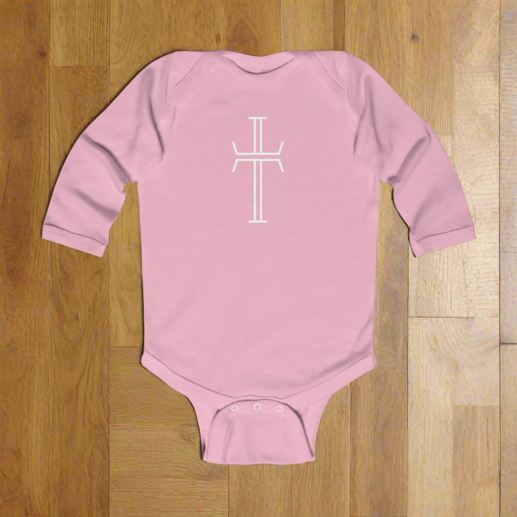 Pink baby onesie with a white cross design on a wood floor background