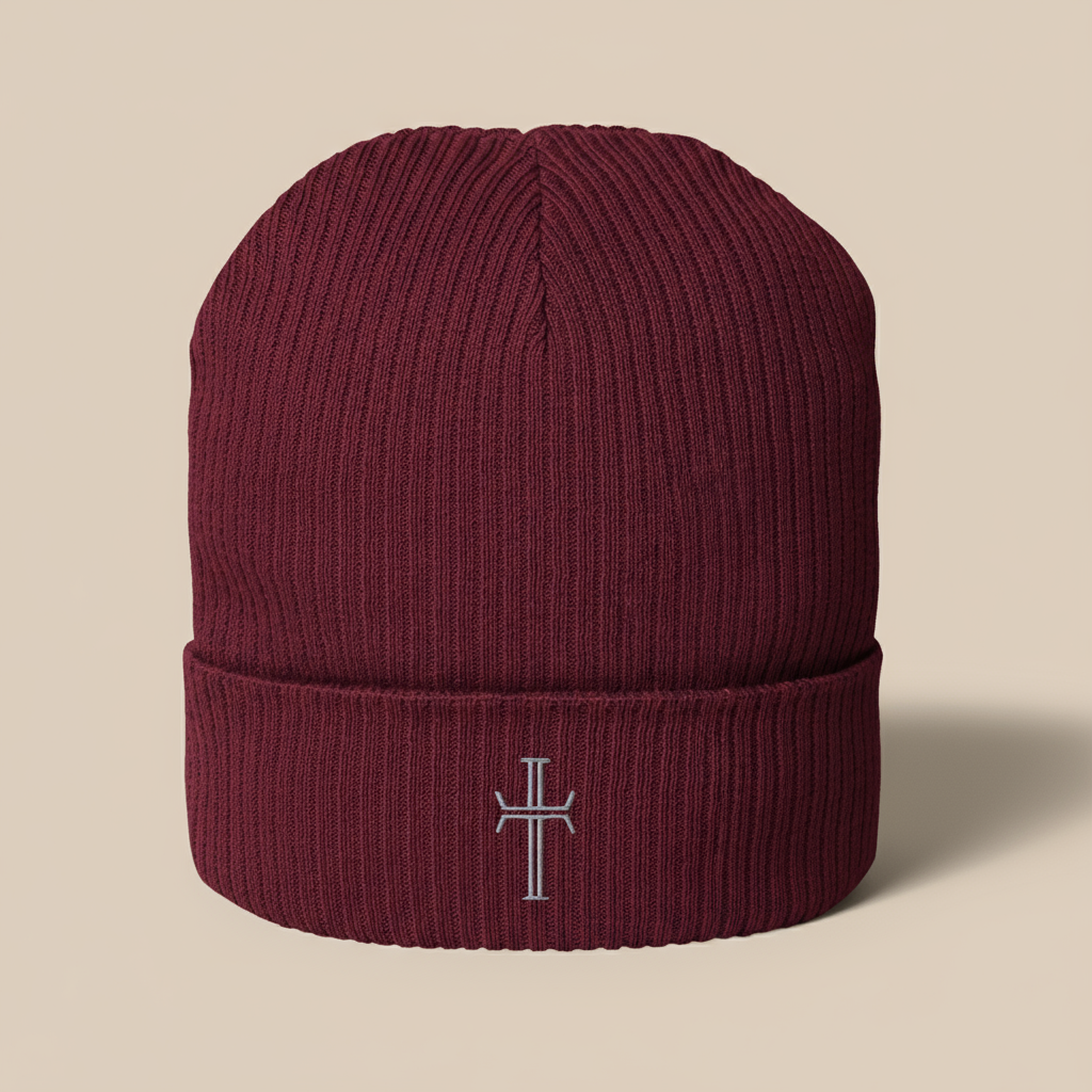 Burgundy knit beanie with gray crucifix embroidered at center of the folded cuff