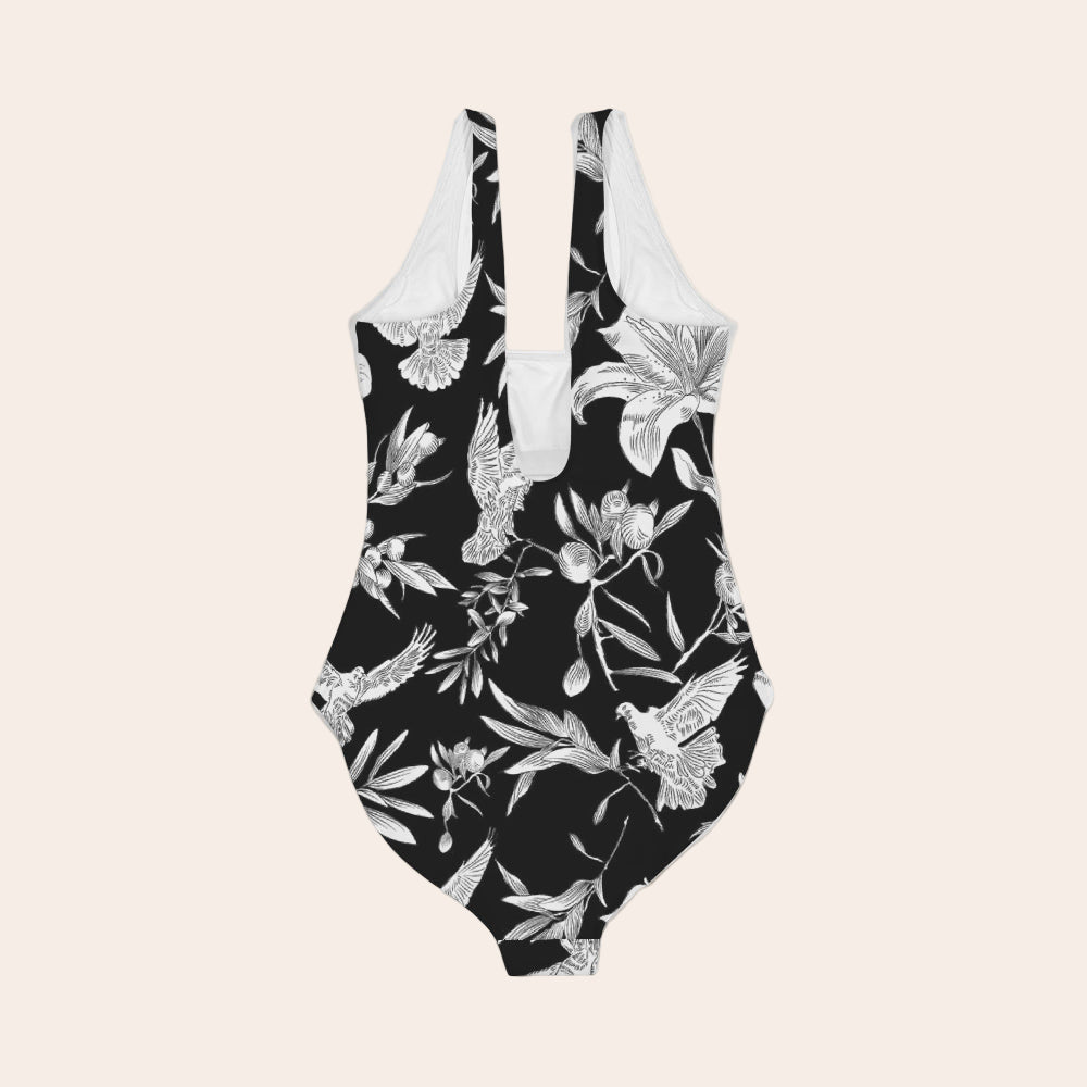 Black swimsuit with white floral pattern laying flat against a light gray background