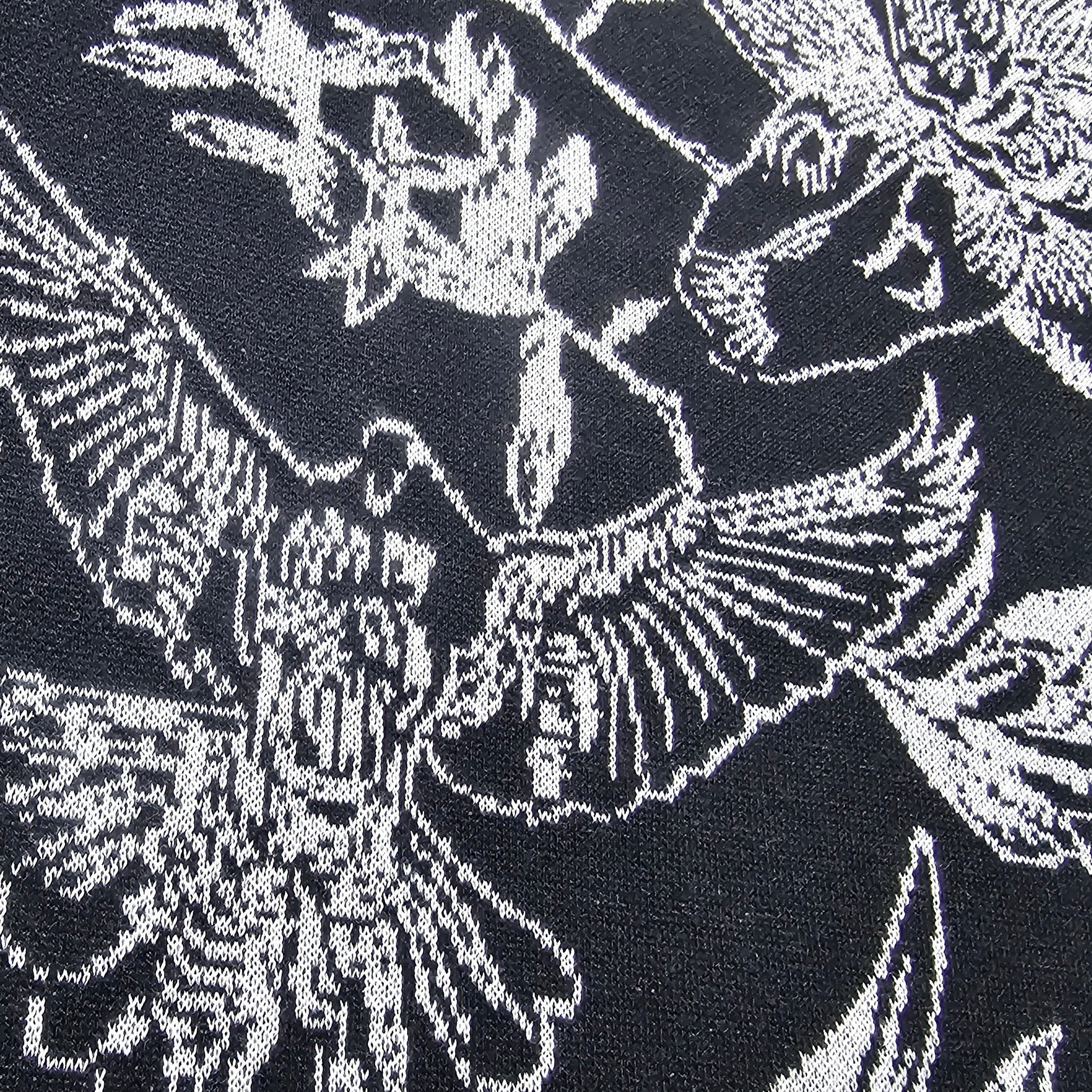 Close-up of a black and white knitted sweater with white floral and dove pattern