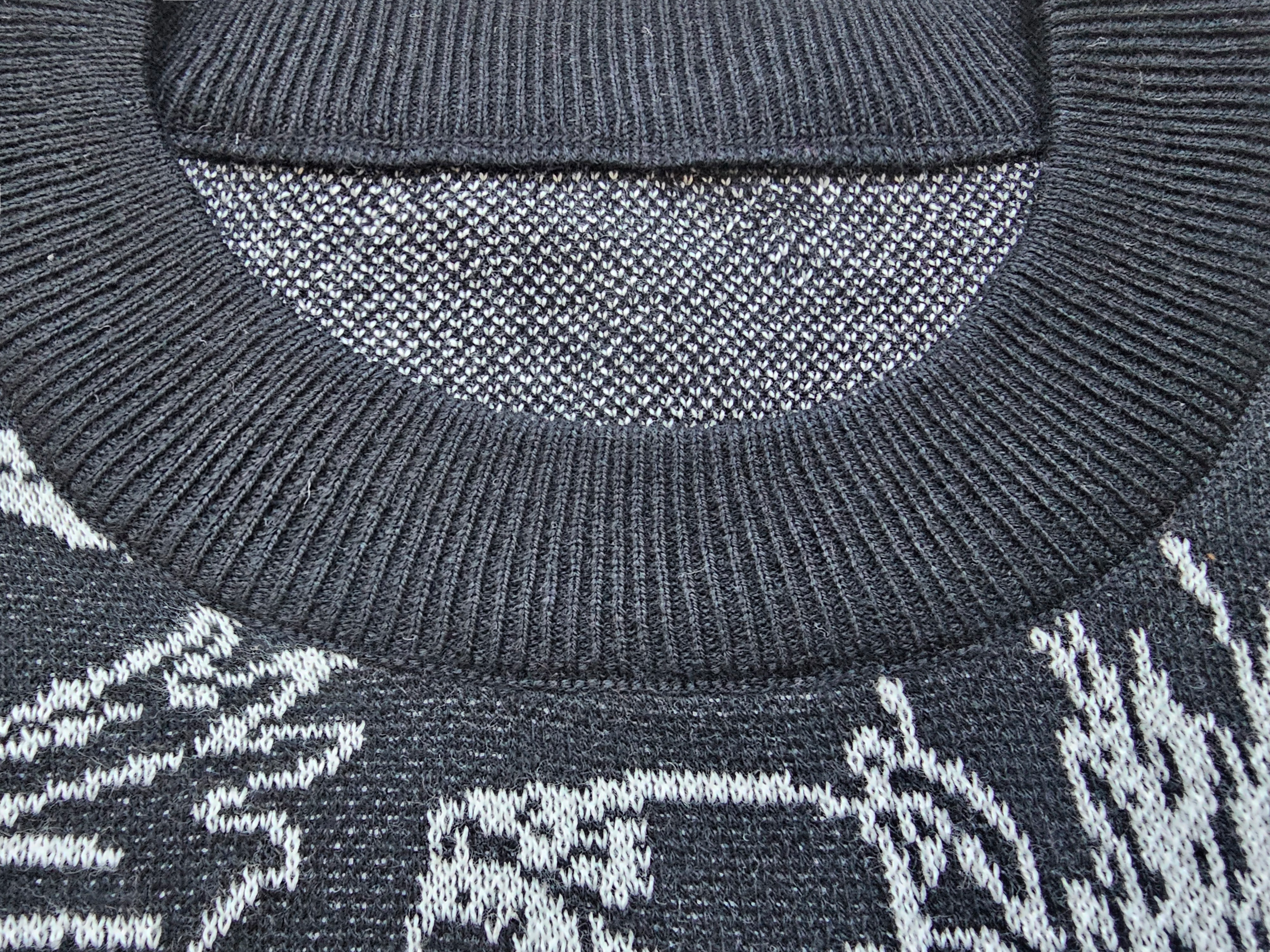 Close-up of a black sweater with a patterned design on the collar and chest area.