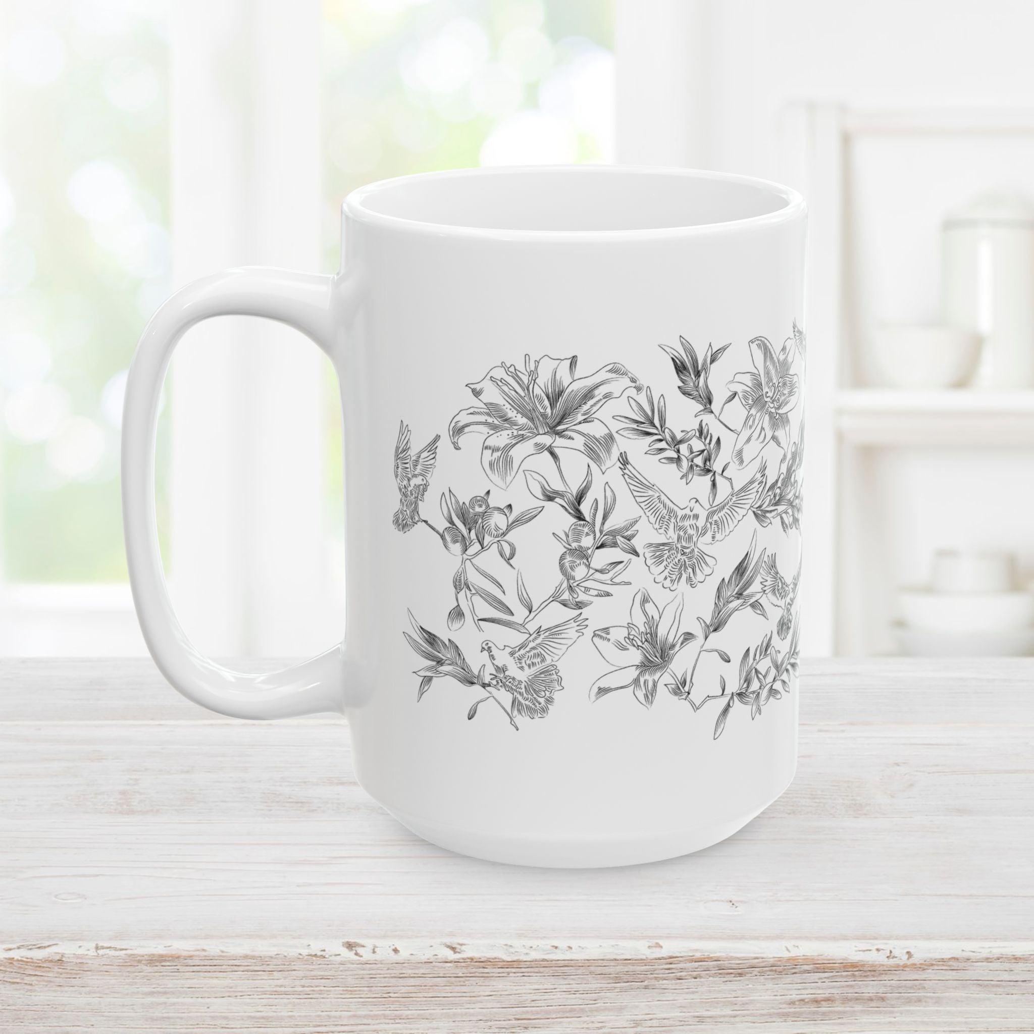 White mug with black floral and dove design on a wooden surface.