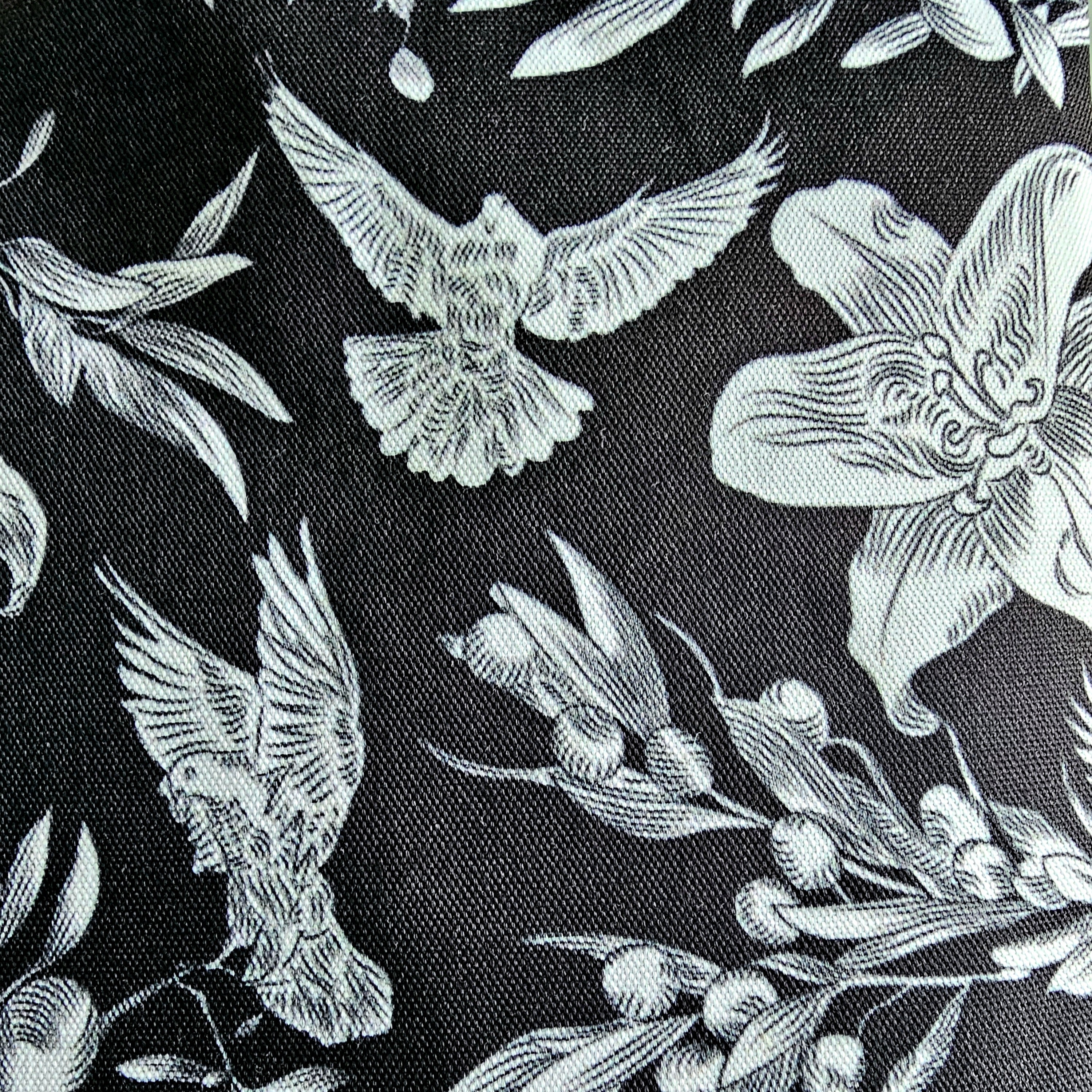 Enlarged image of black canvas tote bag with white dove and floral pattern throughout.