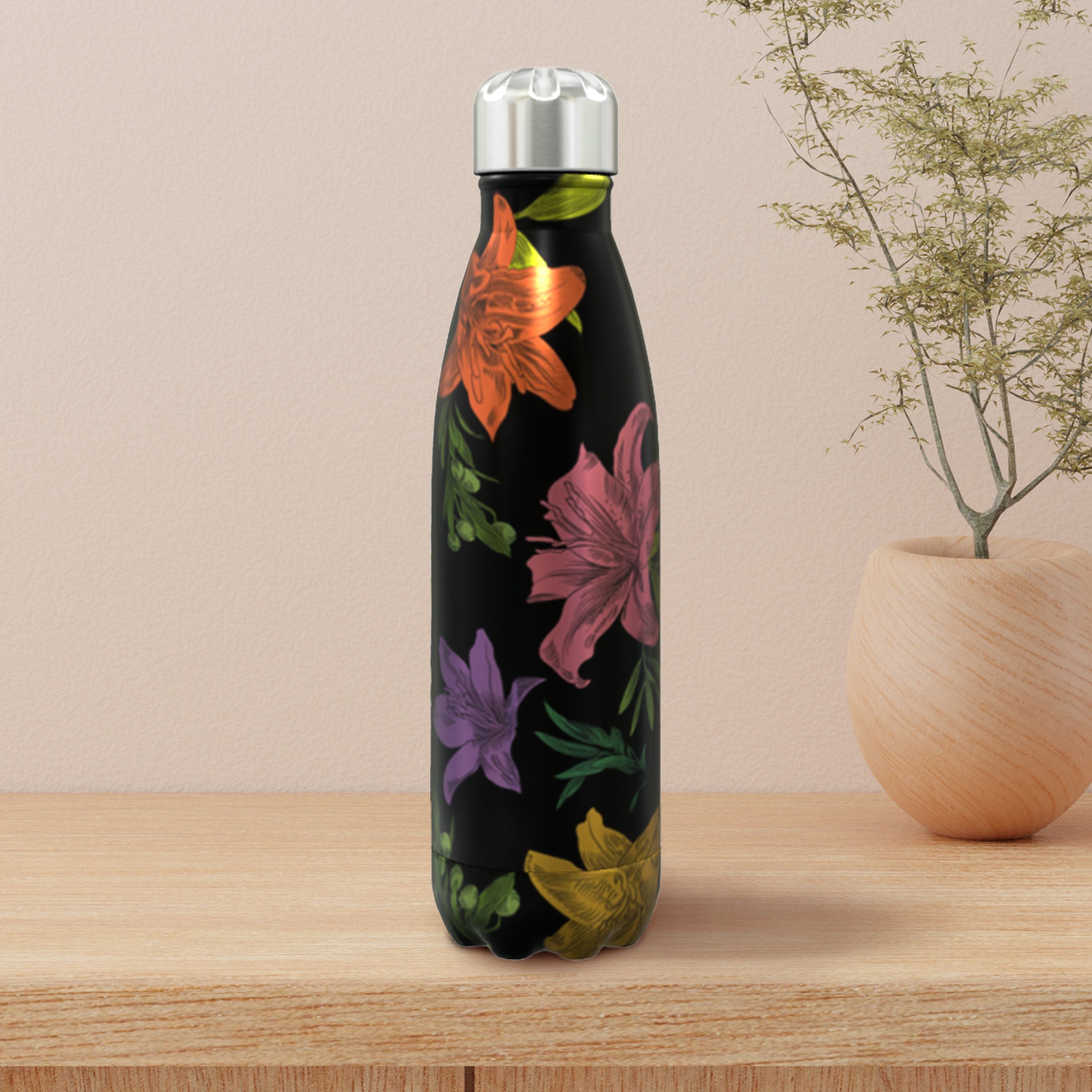 Floral-patterned water bottle on a wooden surface with a plant in the background