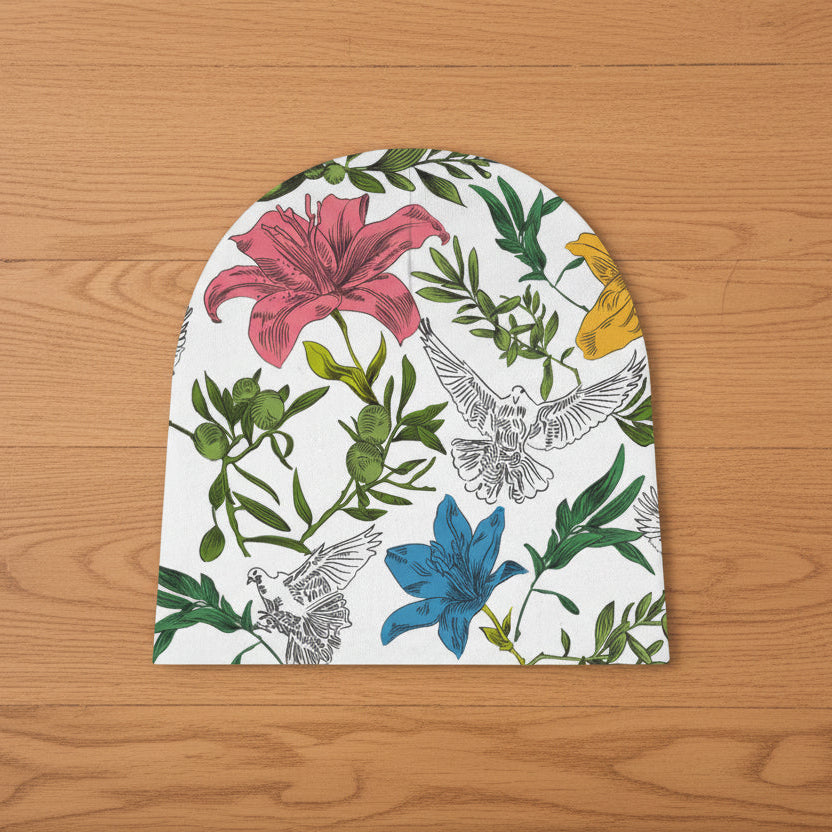 Floral and dove patterned baby beanie on a white background laying on a wood floor