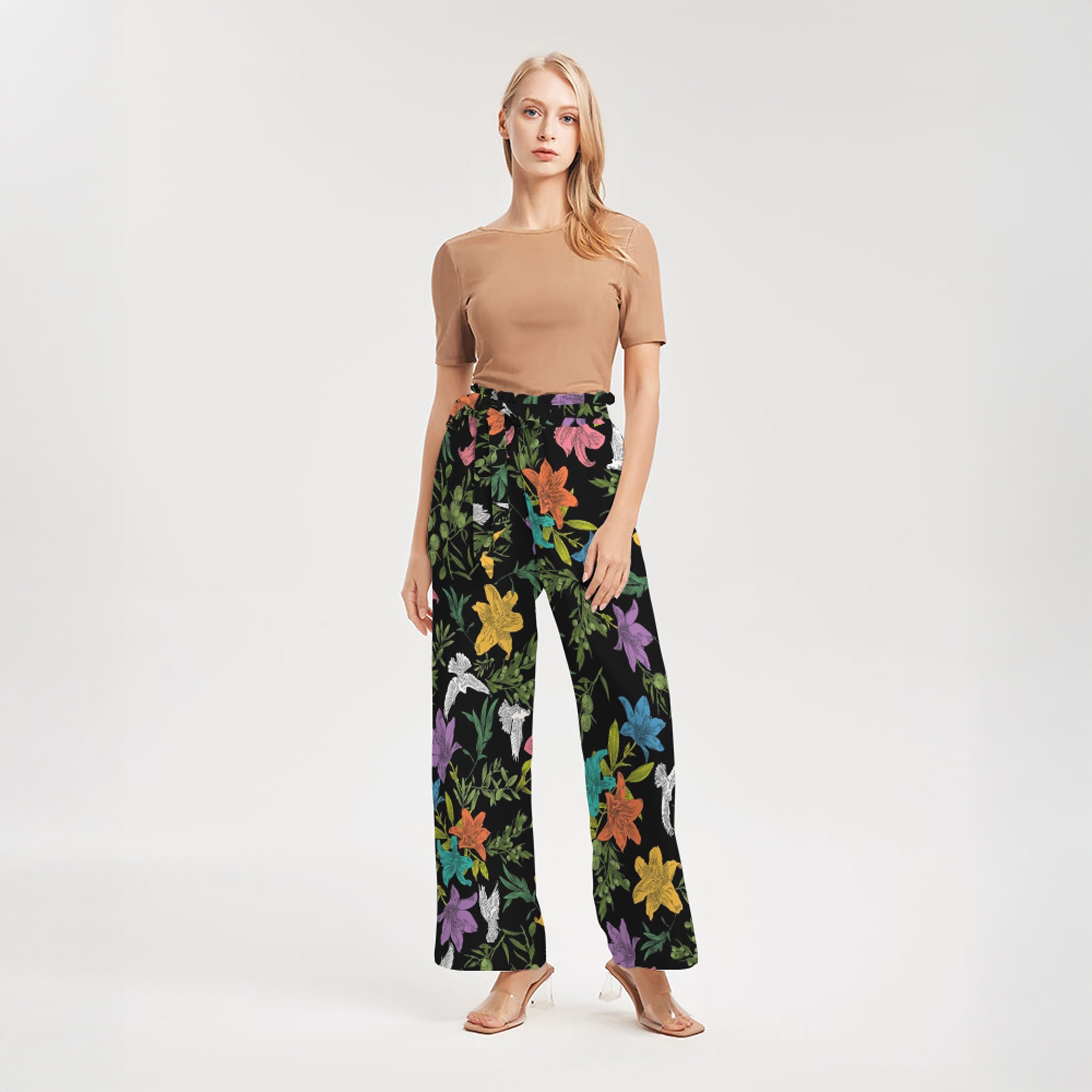 Woman wearing a brown top and colorful floral pants on a white background