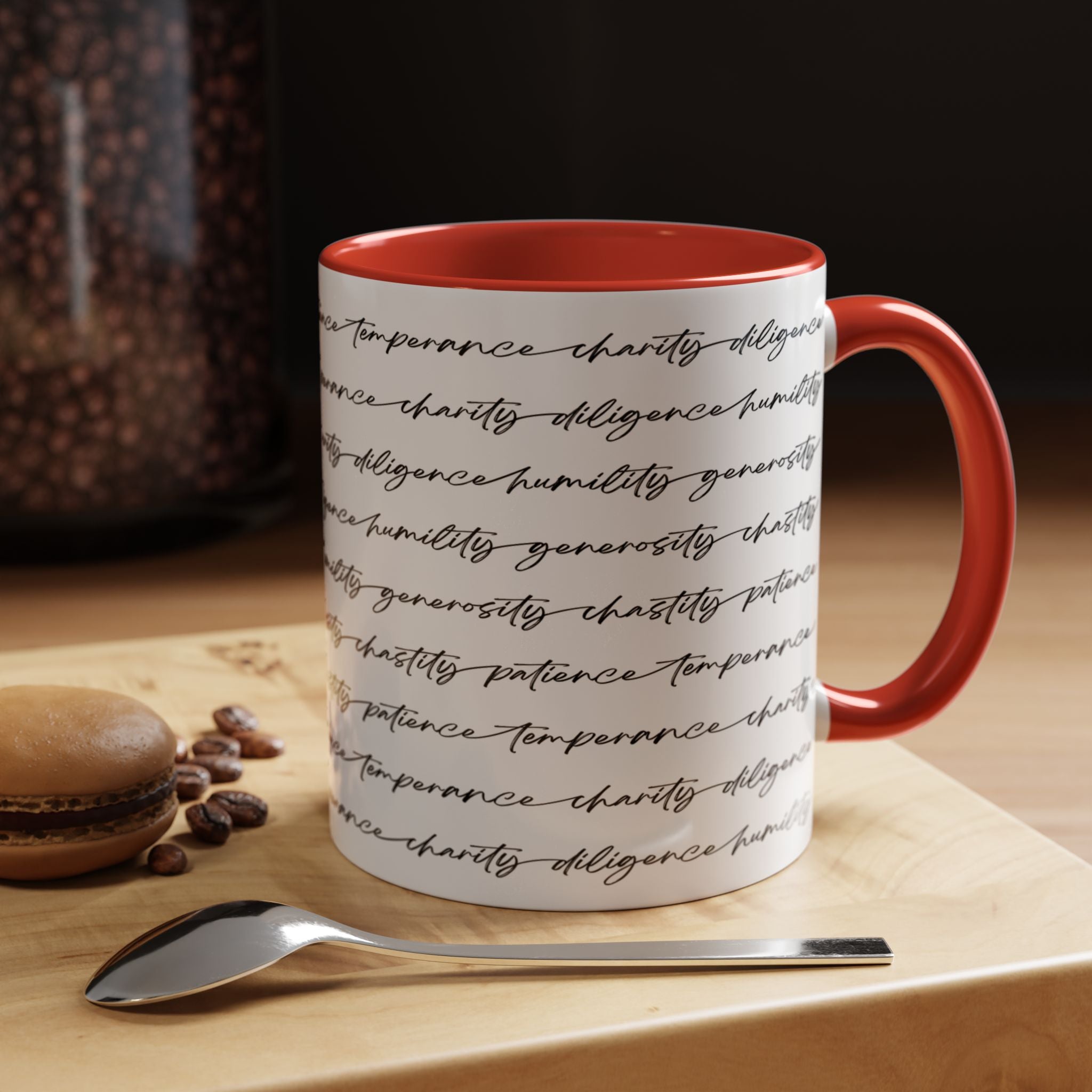 White mug with the seven virtues scripted along the outside, with blue interior and handle on a wooden surface with coffee beans and a spoon.
