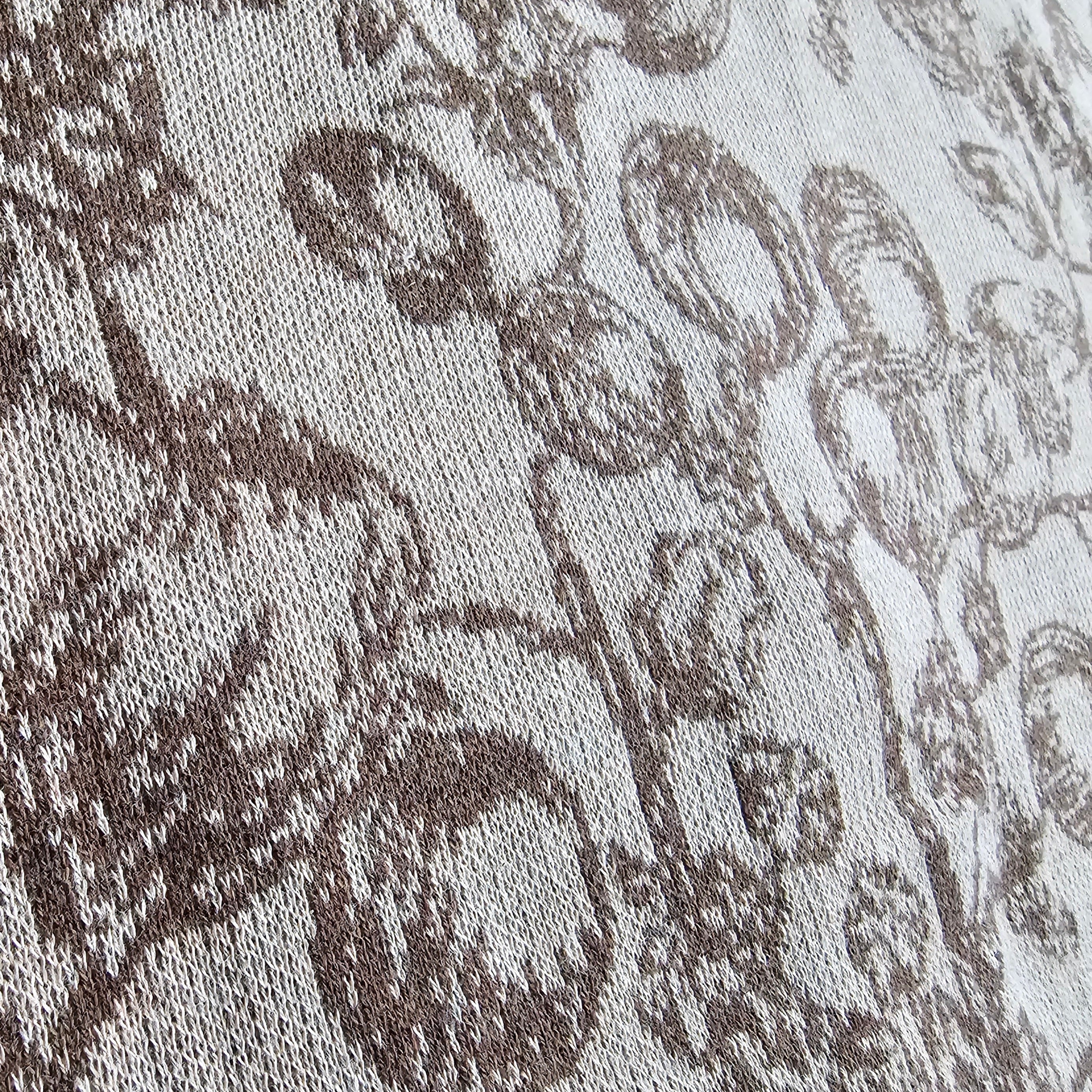 Close-up of a textured knitted fabric with a floral pattern on a neutral background