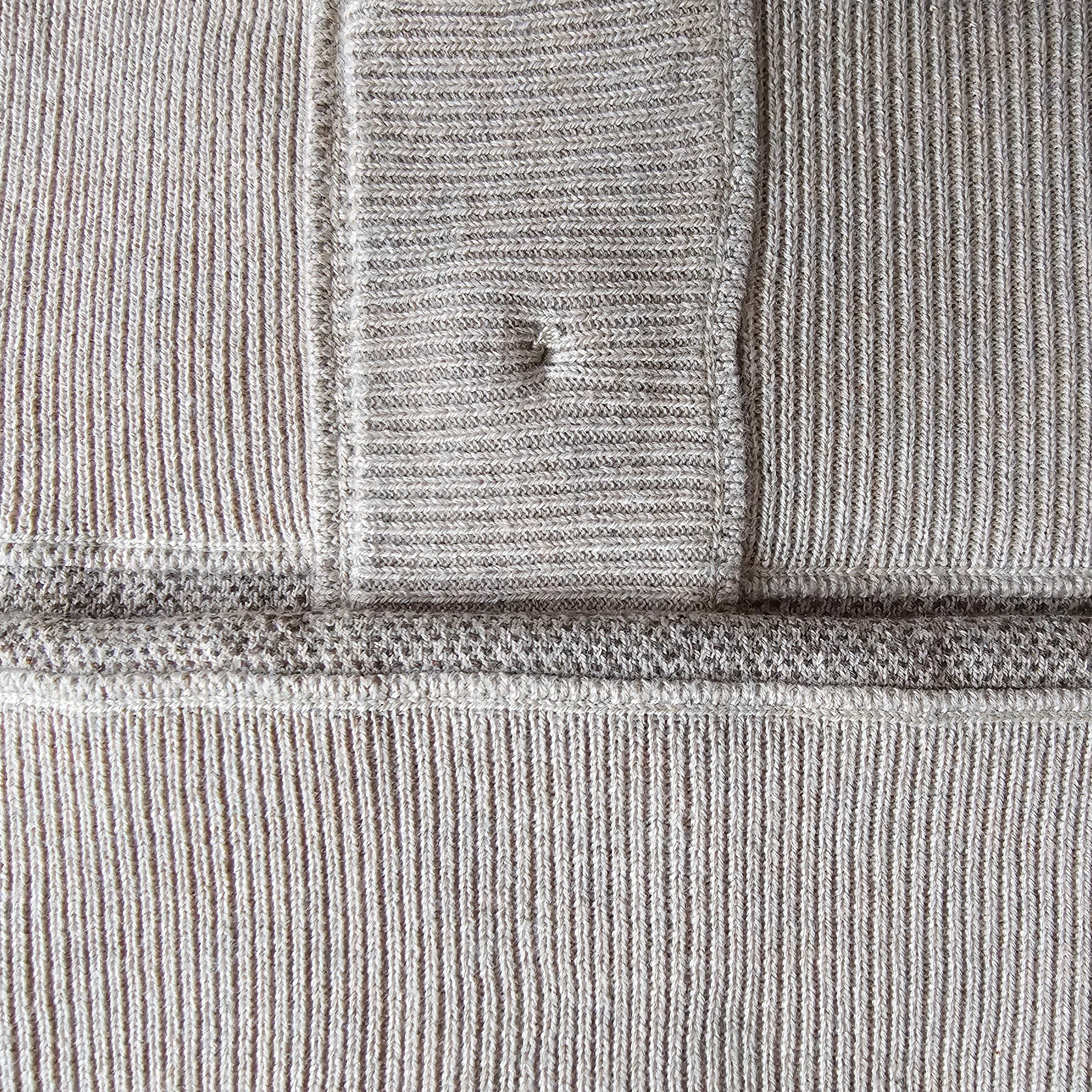 Close-up of neutral-colored, textured knit fabric revealing fully knitted seams and binding.