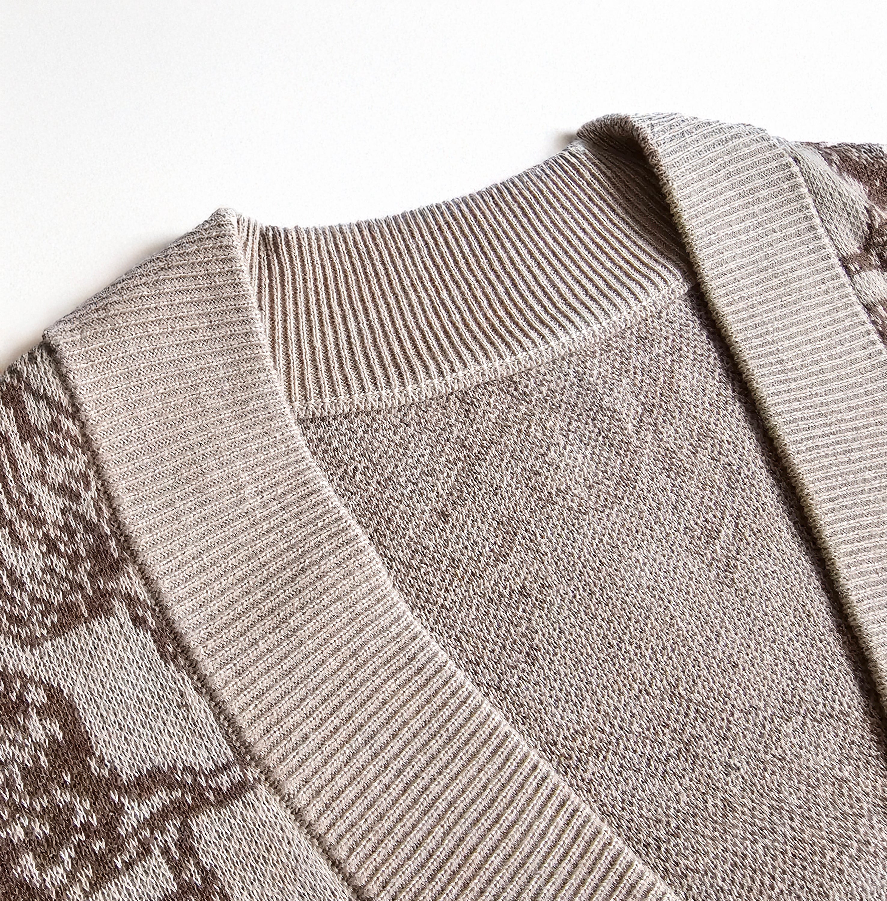 Close-up of a gray sweater with patterned sleeves on a light background