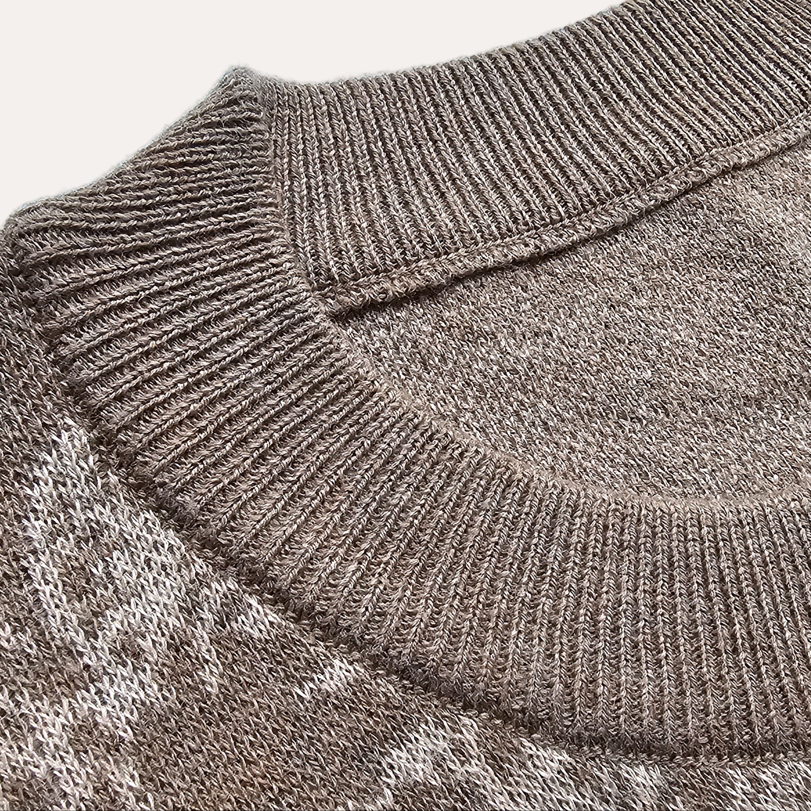 Close-up of a gray sweater with a patterned design on a light blue background