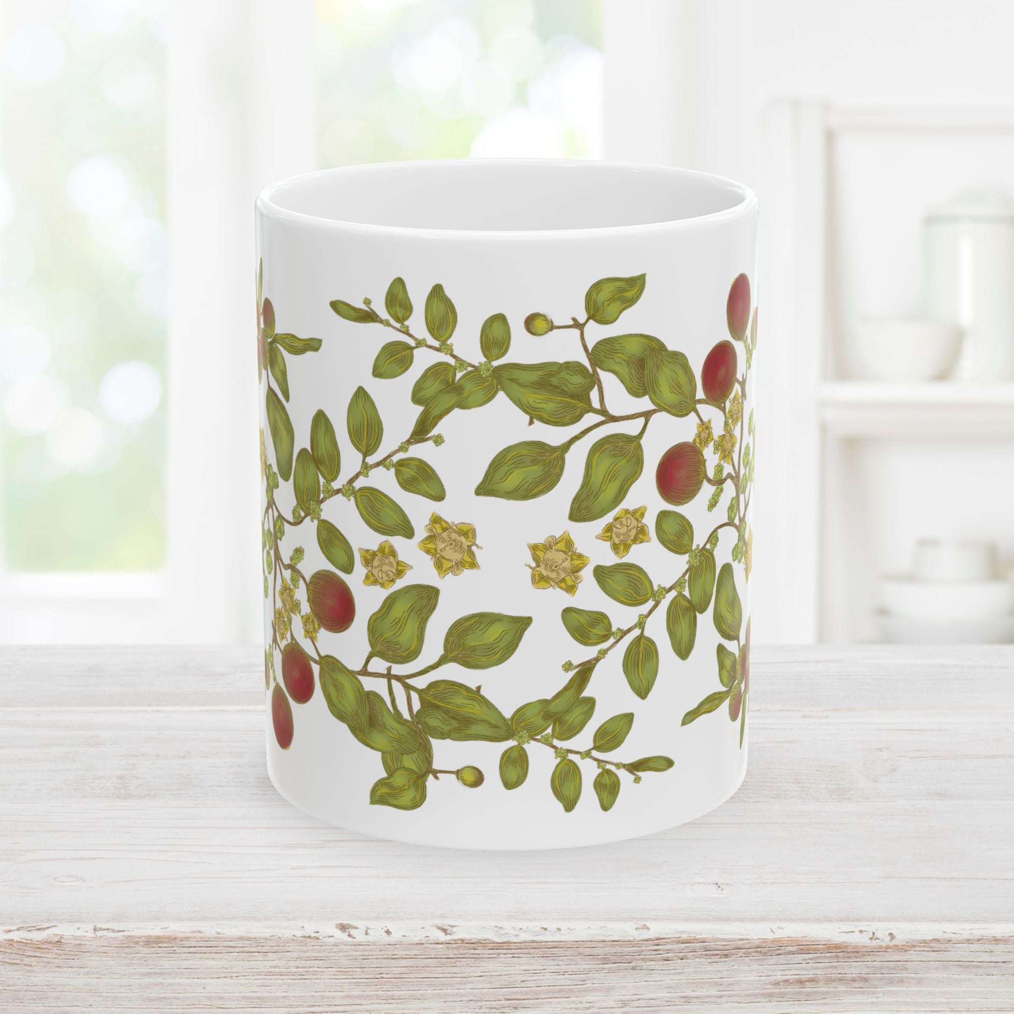 Front side of white mug with floral and berry leaf pattern on a wooden surface.