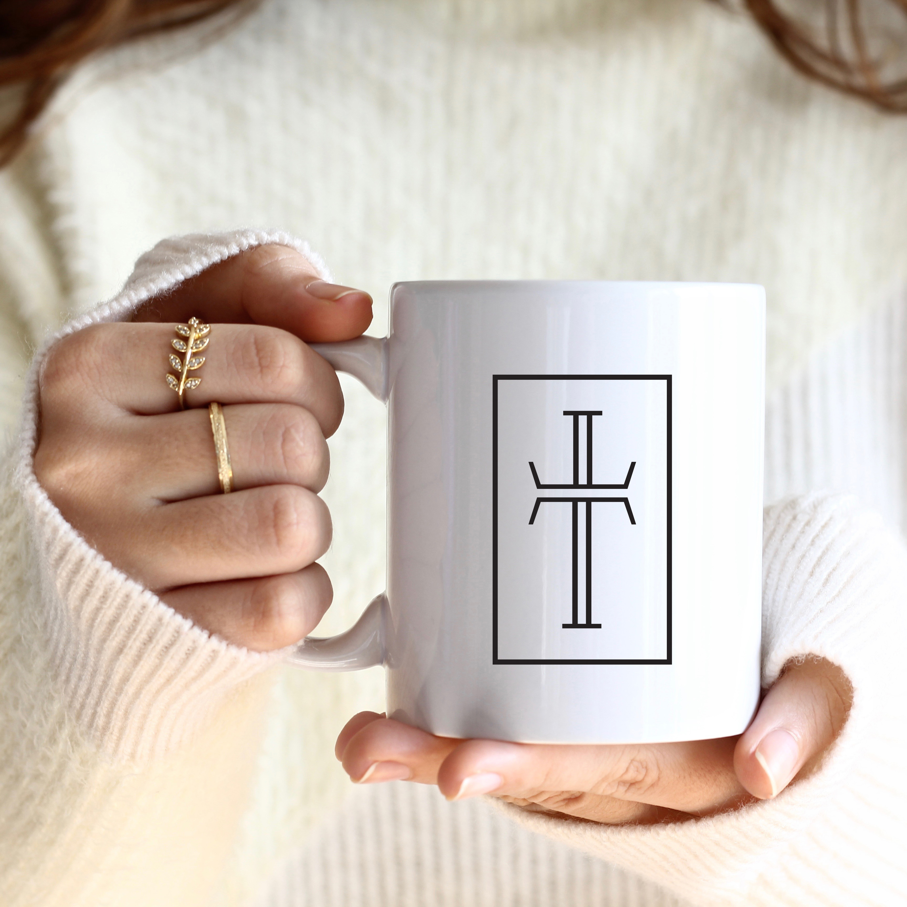 A woman's hands are holding a mug with the Purpose logo cross