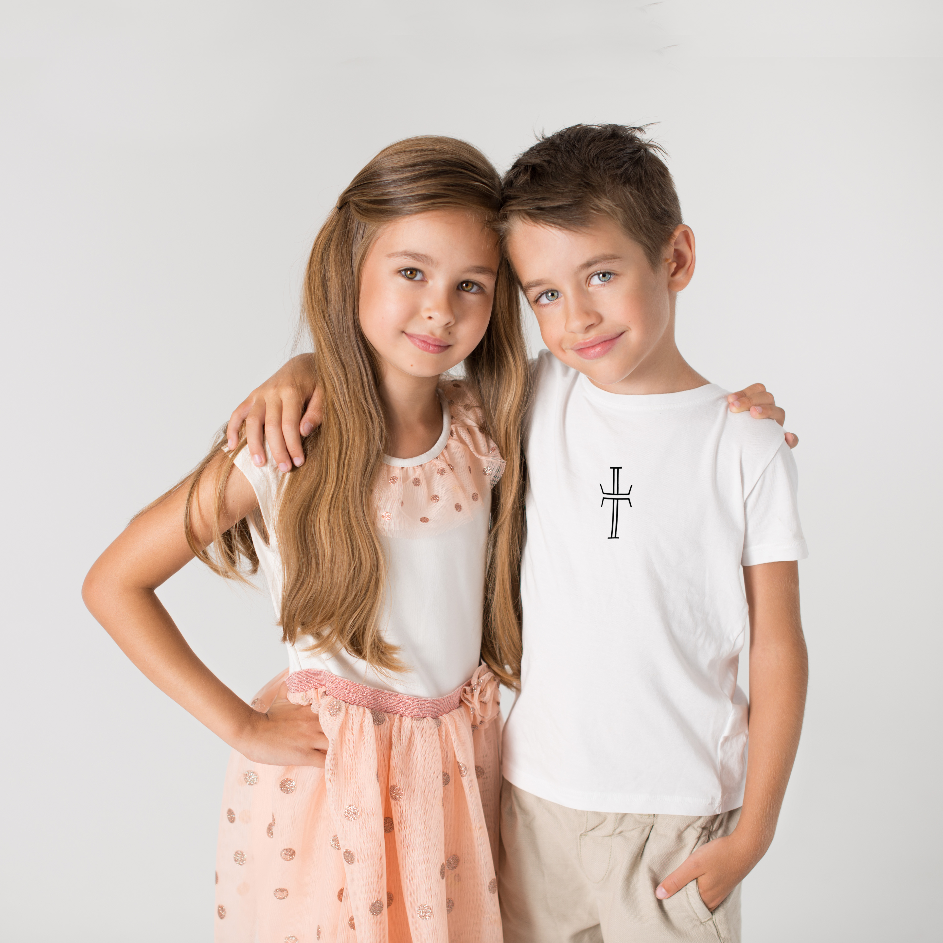 A 9 year old boy and girl pose with one are behind the other, smiling at the camera.