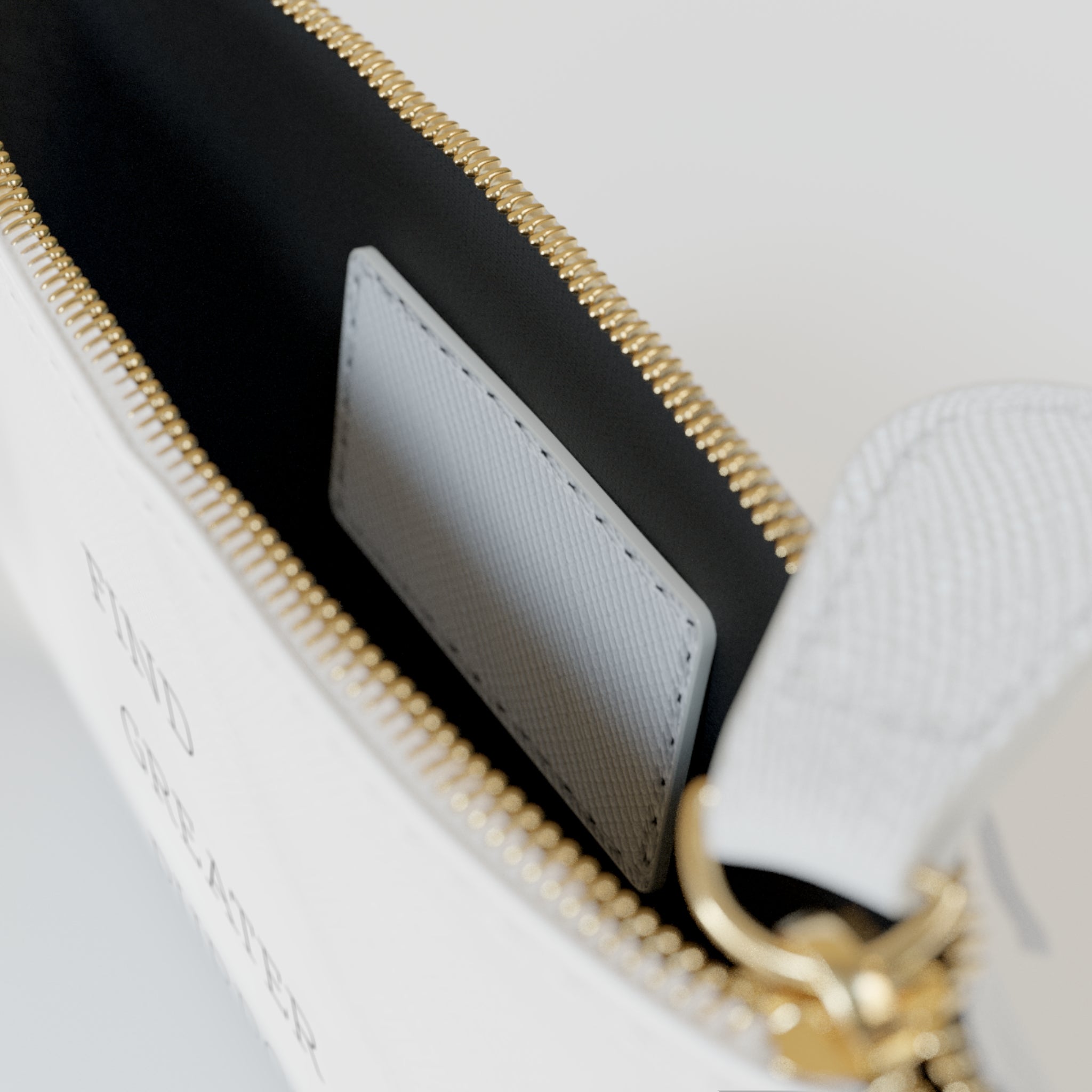 The inner main compartment of a white clutch with black interior and a white rectangular leather-textured patch sewn onto the inside. The zipper is gold-tone with a white, tear-shaped zipper pull.