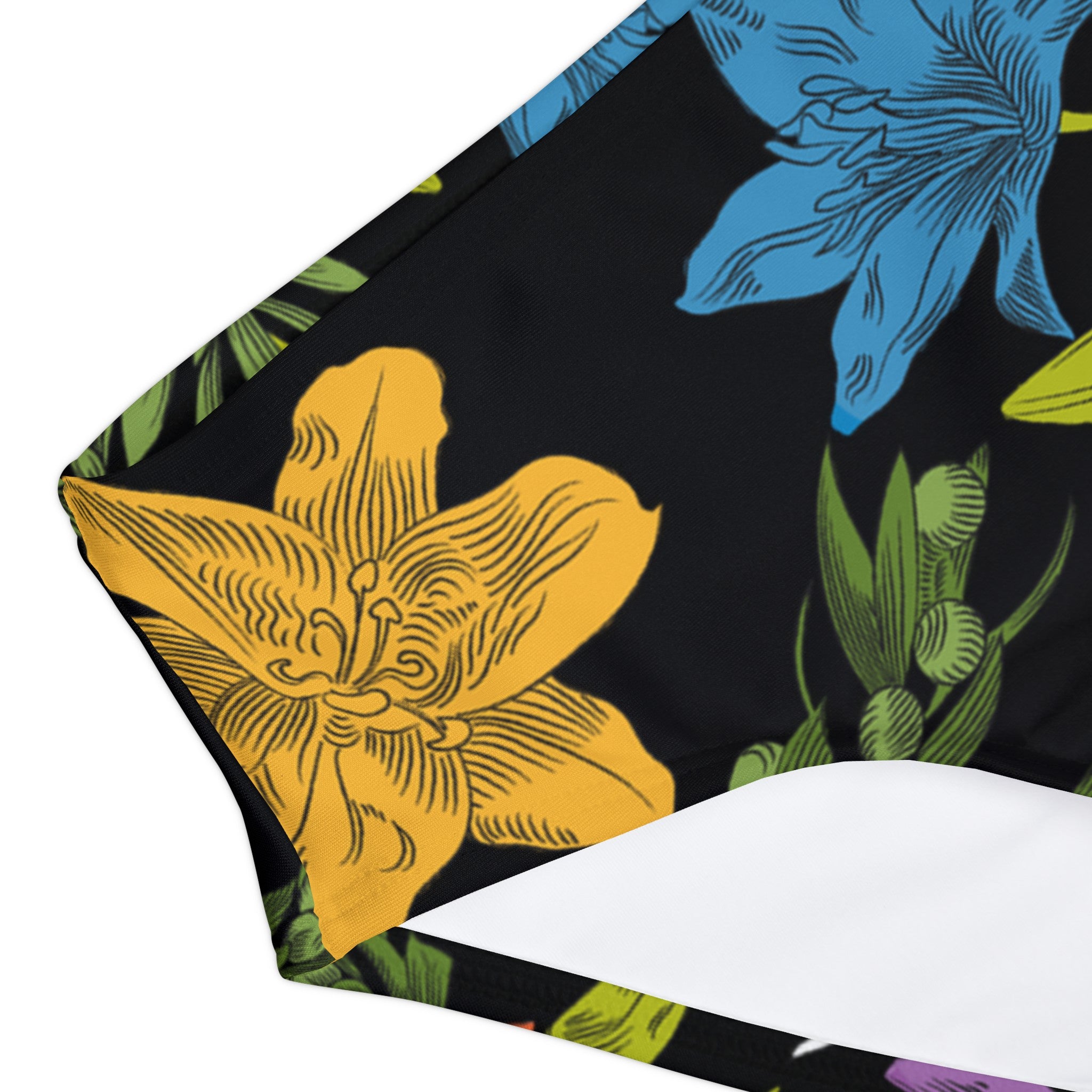 Close-up of the swim bottoms showing the finer details of the all-over, multi-colored pattern with flowers, olive branches, and doves.