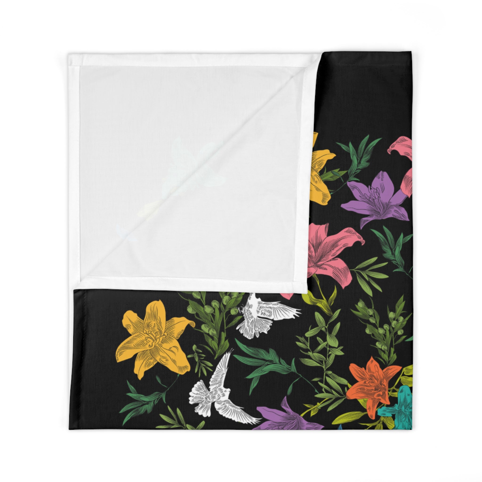 A folded, black knit, baby swaddle blanket with multi-colored, all-over print of doves, flowers, and olive branches, revealing a folded corner that displays the white underside.