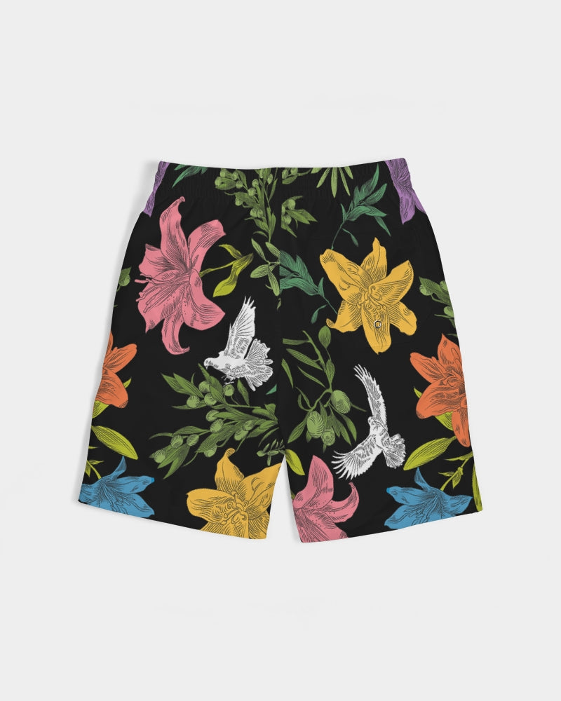 Back angle of black board shorts with an all-over, multi-colored pattern of flowers, olive branches, and doves, has white external ties and elastic waistband.