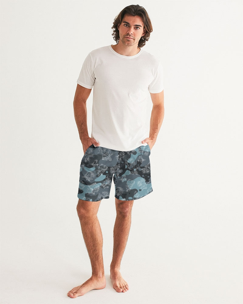 The a male model wearing a white tee shirt and blue camo board shorts that have an all-over print of swimming carp rendered in white.