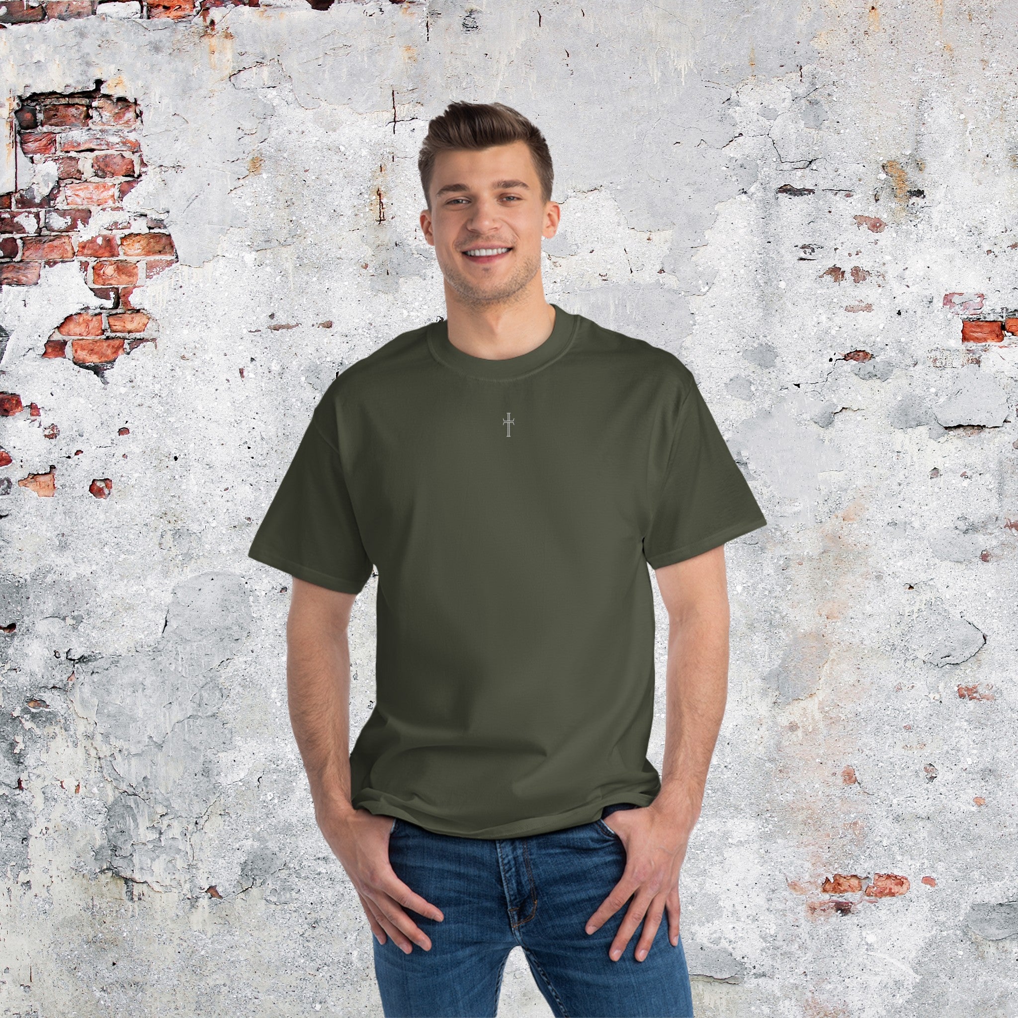 A tall slender man in blue jeans is broadly smiling while wearing a roomy army green crewneck tee shirt with the small Purpose cross logo centered on the upper chest.