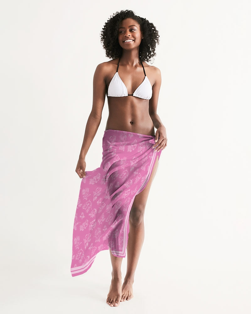 A female model wears a white string bikini and has a pink, all-over printed, translucent, cover-up scarf tied at her hip. The cover-up displays a white fish pattern and white double border along the edges.