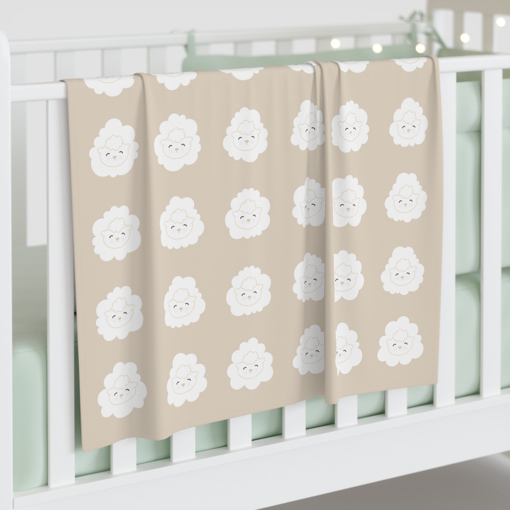Beige blanket with white lamb pattern draped over a crib.