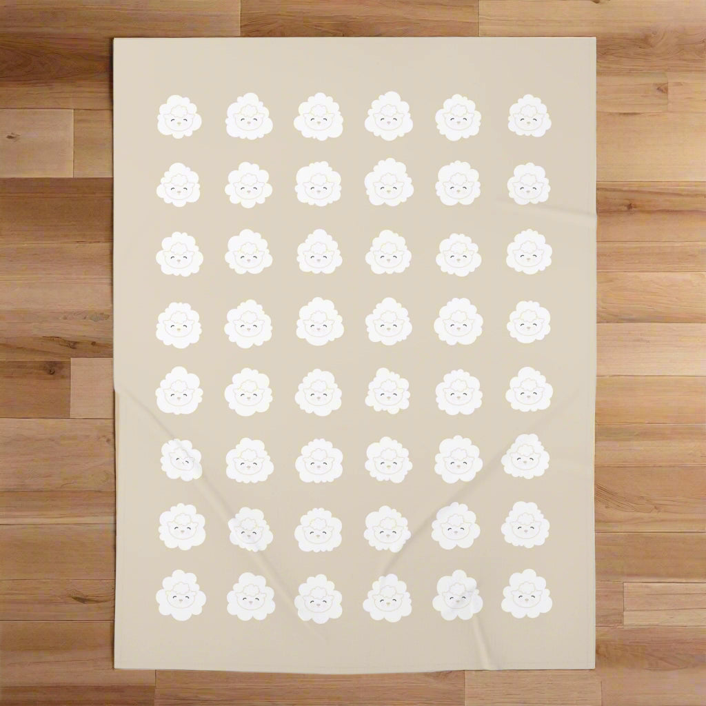 An overhead view of the beige swaddle blanket with an all-over, white, lamb-face pattern in even rows.