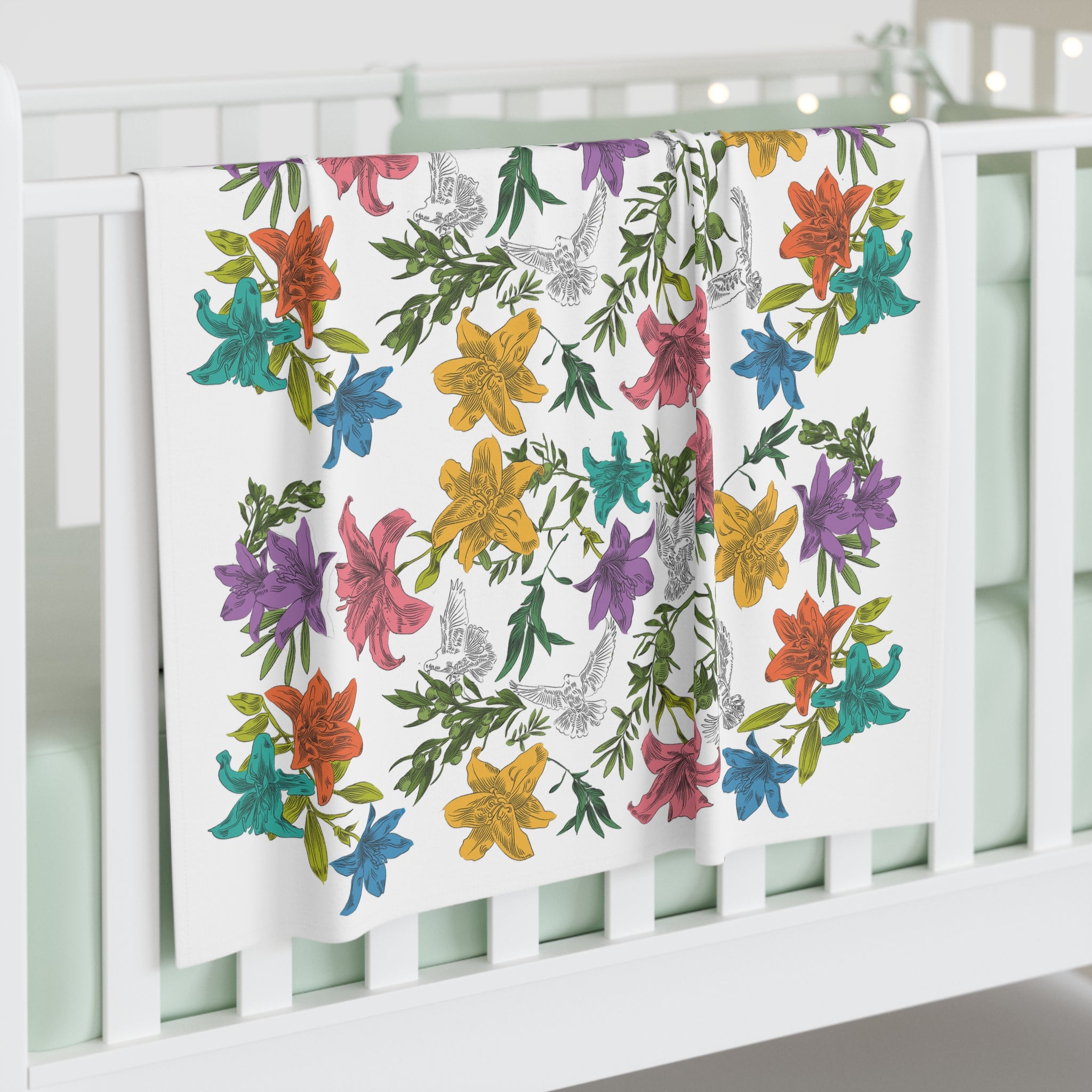 Floral and dove patterned blanket draped over a crib with a white background