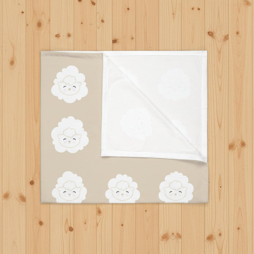 Blanket with white lamb pattern on a beige  background laying on a wood floor
