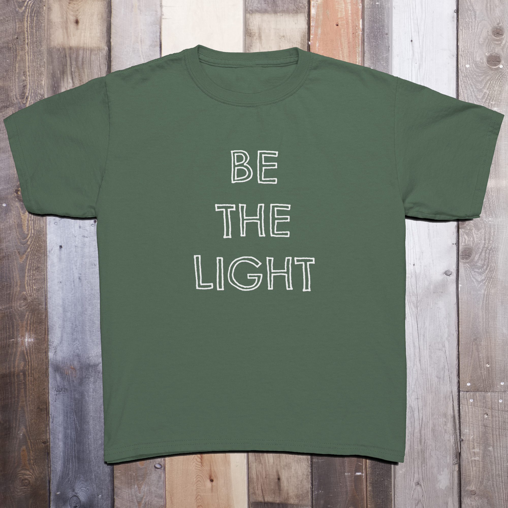 Army green t-shirt with the phrase BE THE LIGHT written in white on the front center of the garment, with each word stacked above the other.