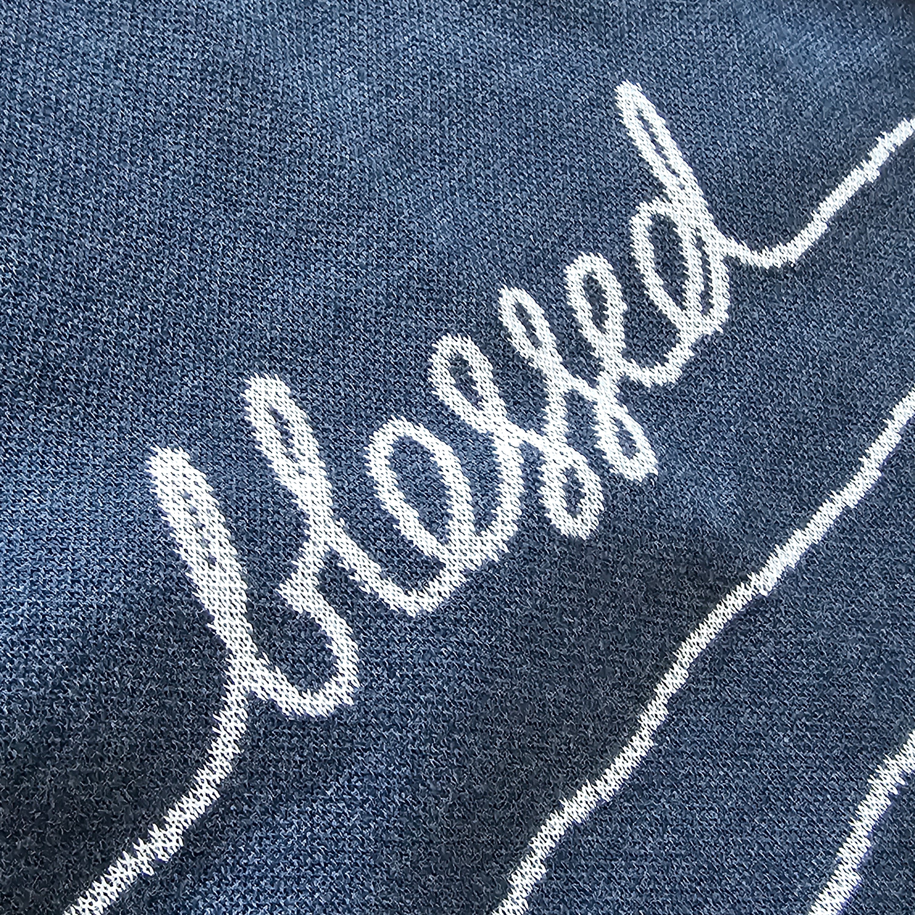 Text 'blessed' embroidered on a blue knit background