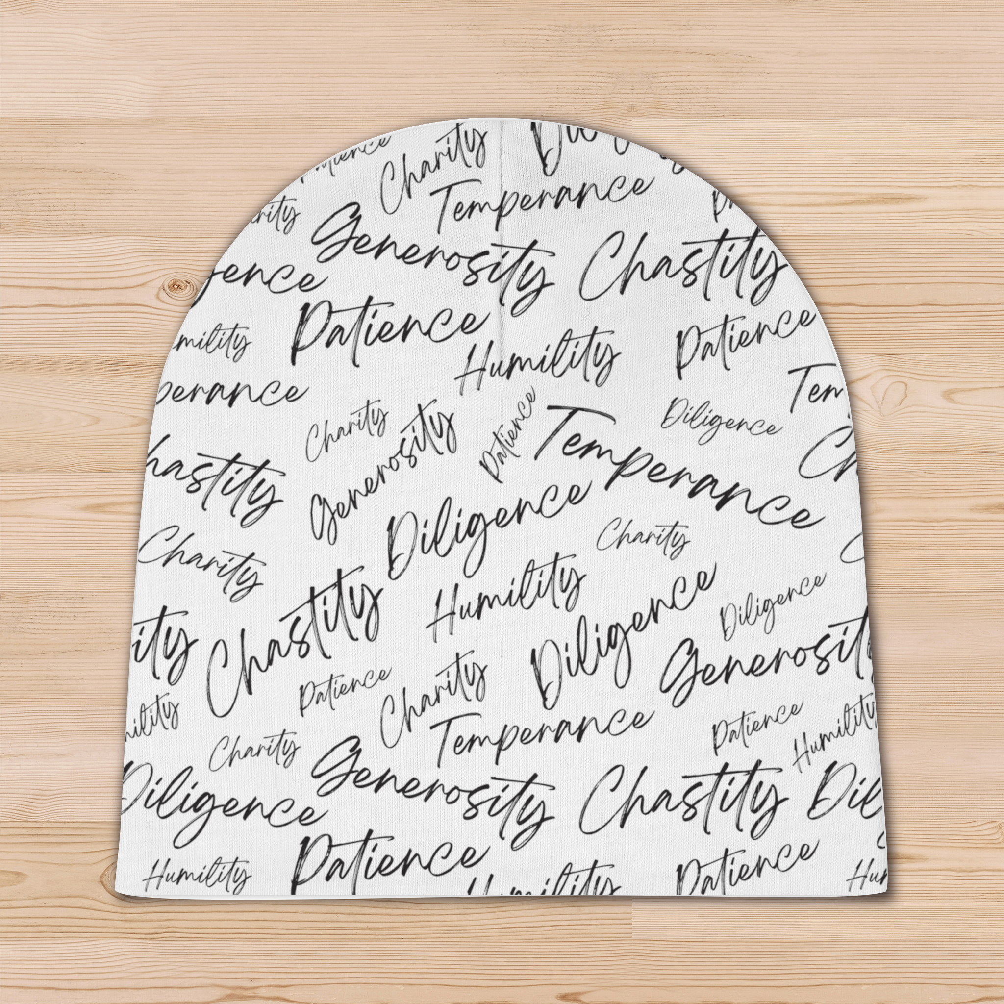 A white, knit, baby beanie with biblical virtues written in black script in a random all-over pattern on the cap without the folded brim.