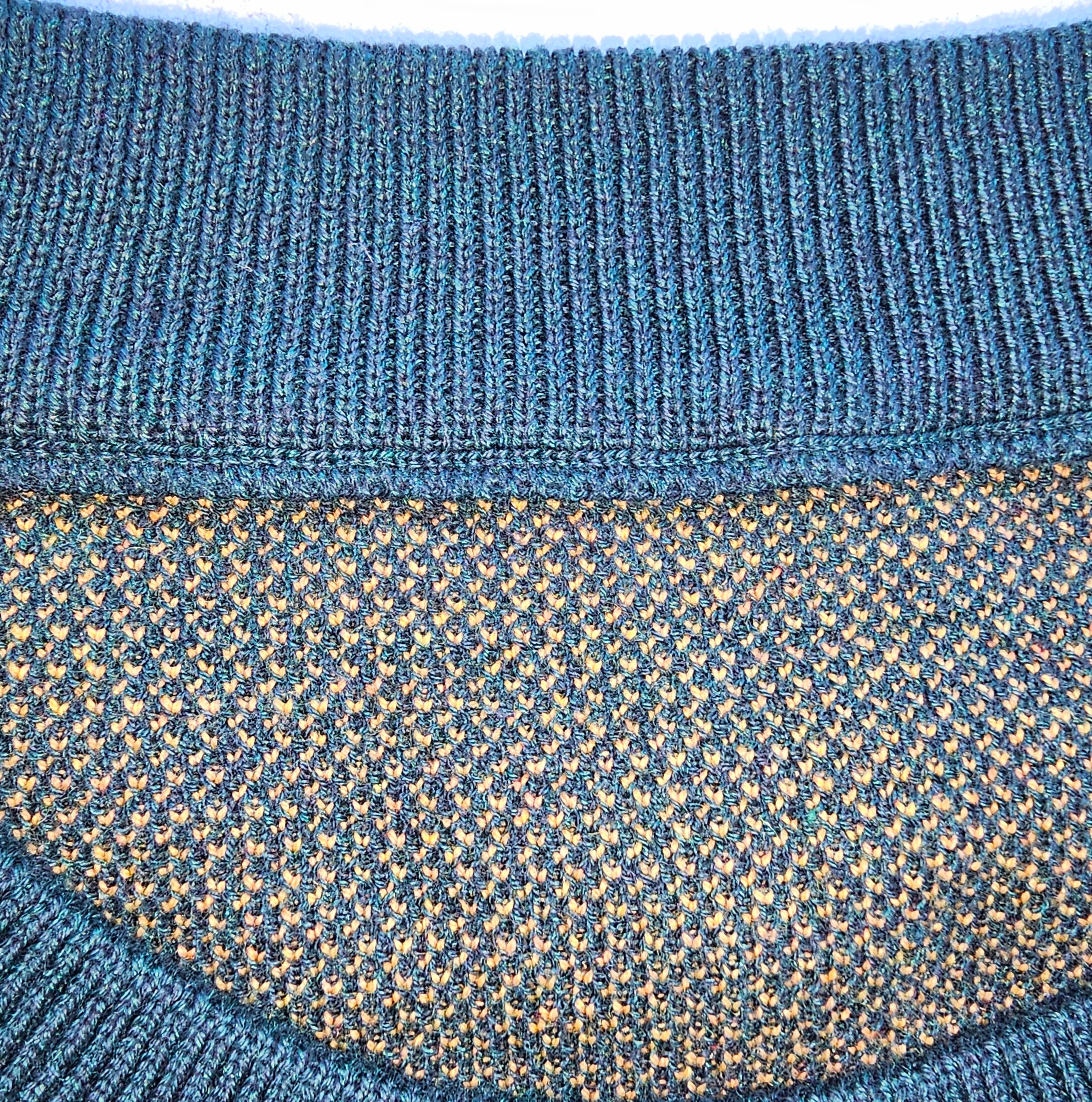 A close-up of the inner rib-knit collar and finished knitted inner edges of the forest green sweater.