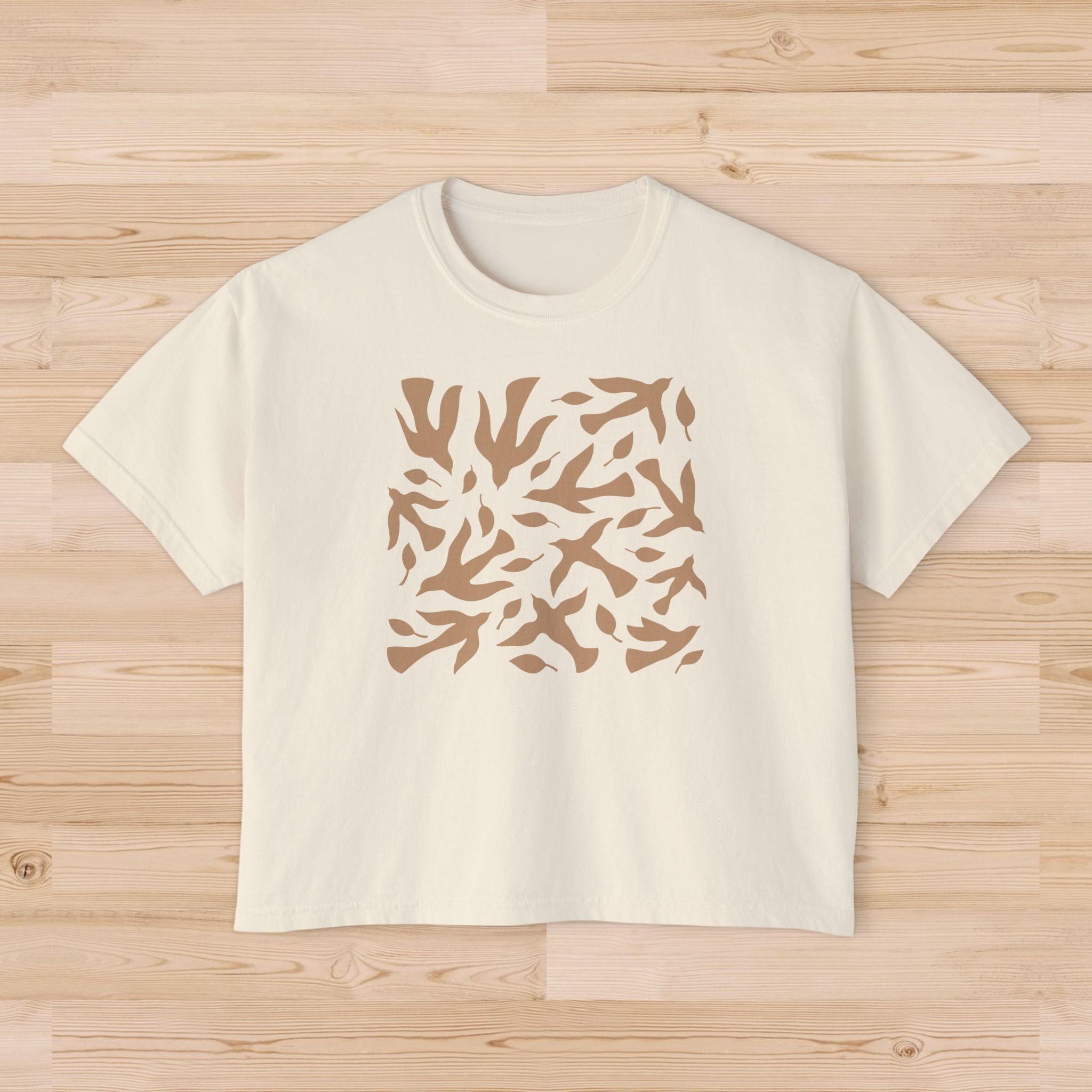 Beige t-shirt with a brown abstract pattern on a wooden surface