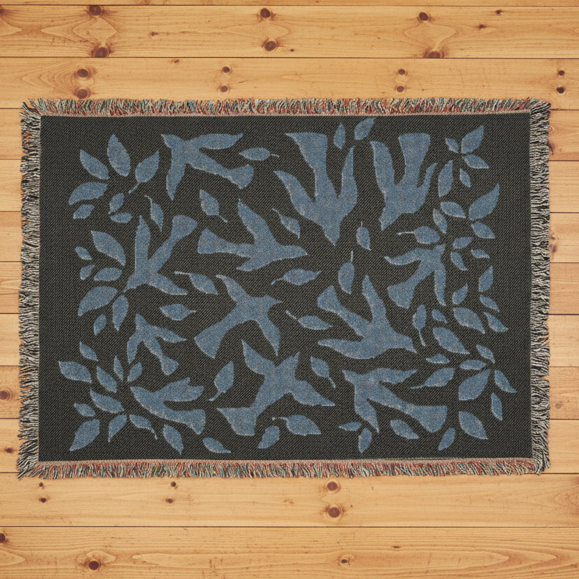 Floral-patterned throw blanket with blue leaves with a dark background on a wood floor