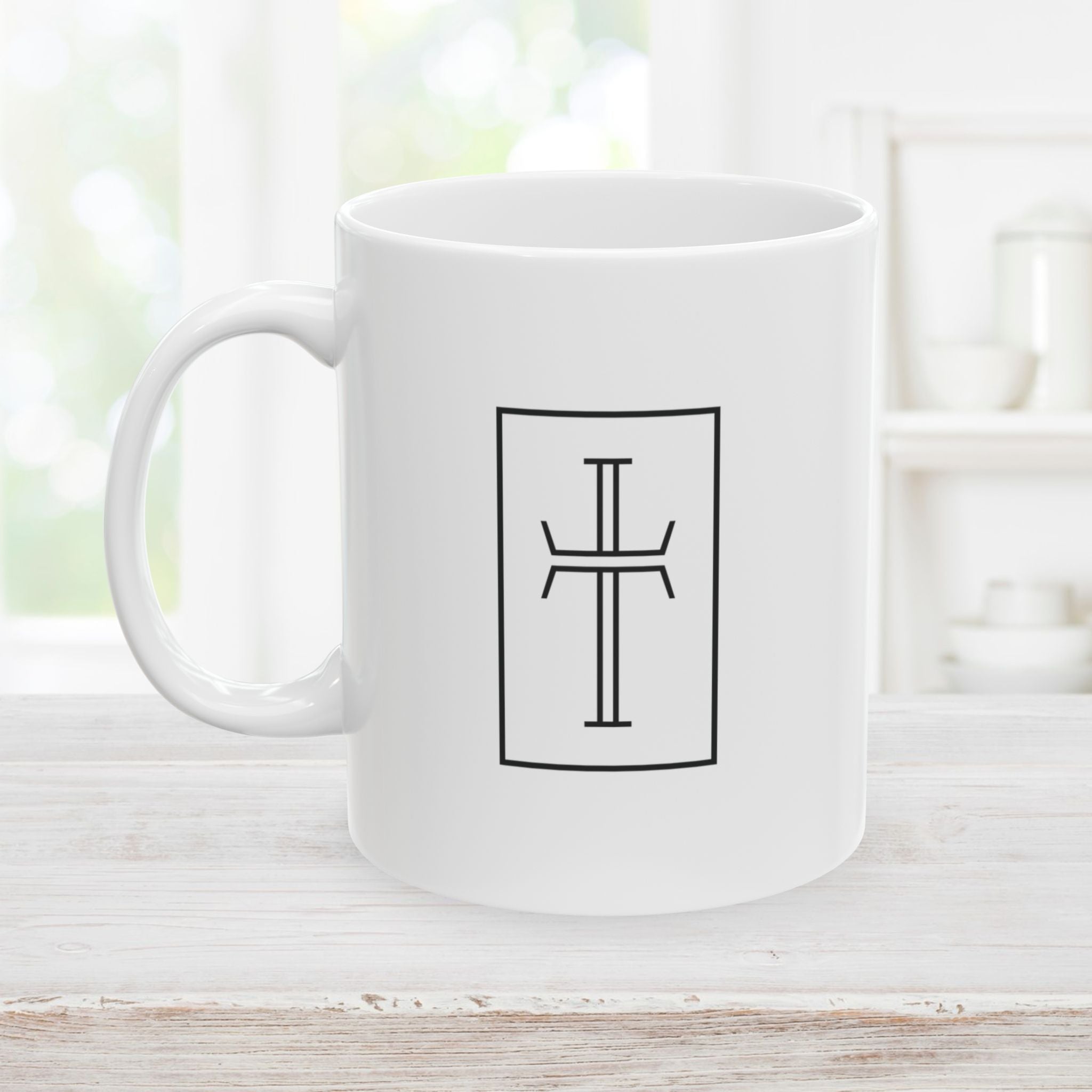 Right side of 11oz white mug with a black cross on a light wooden surface.